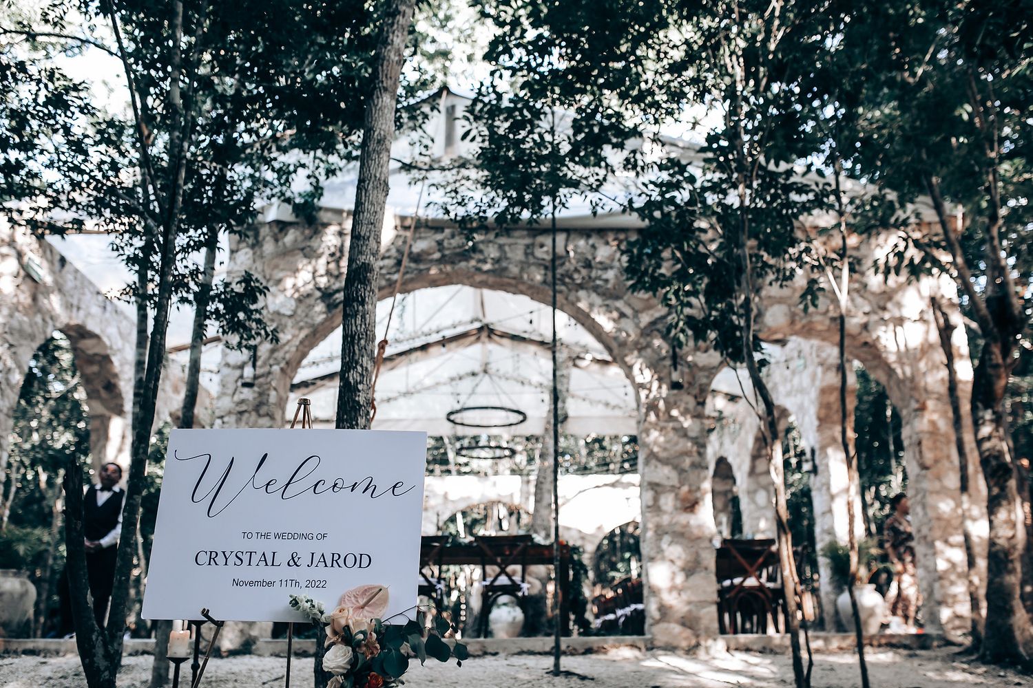 Wedding ceremony setup in a serene outdoor forest venue with white chairs and natural decor.