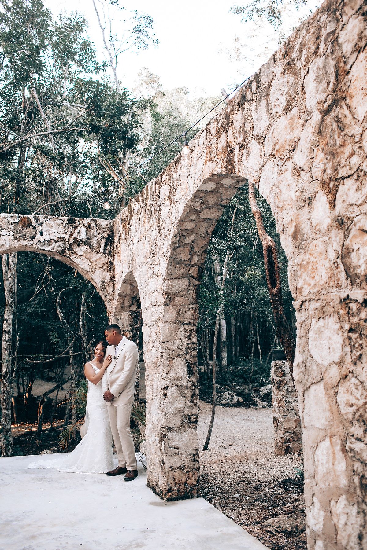 Wedding photo session at ancient stone arches in a forest setting.