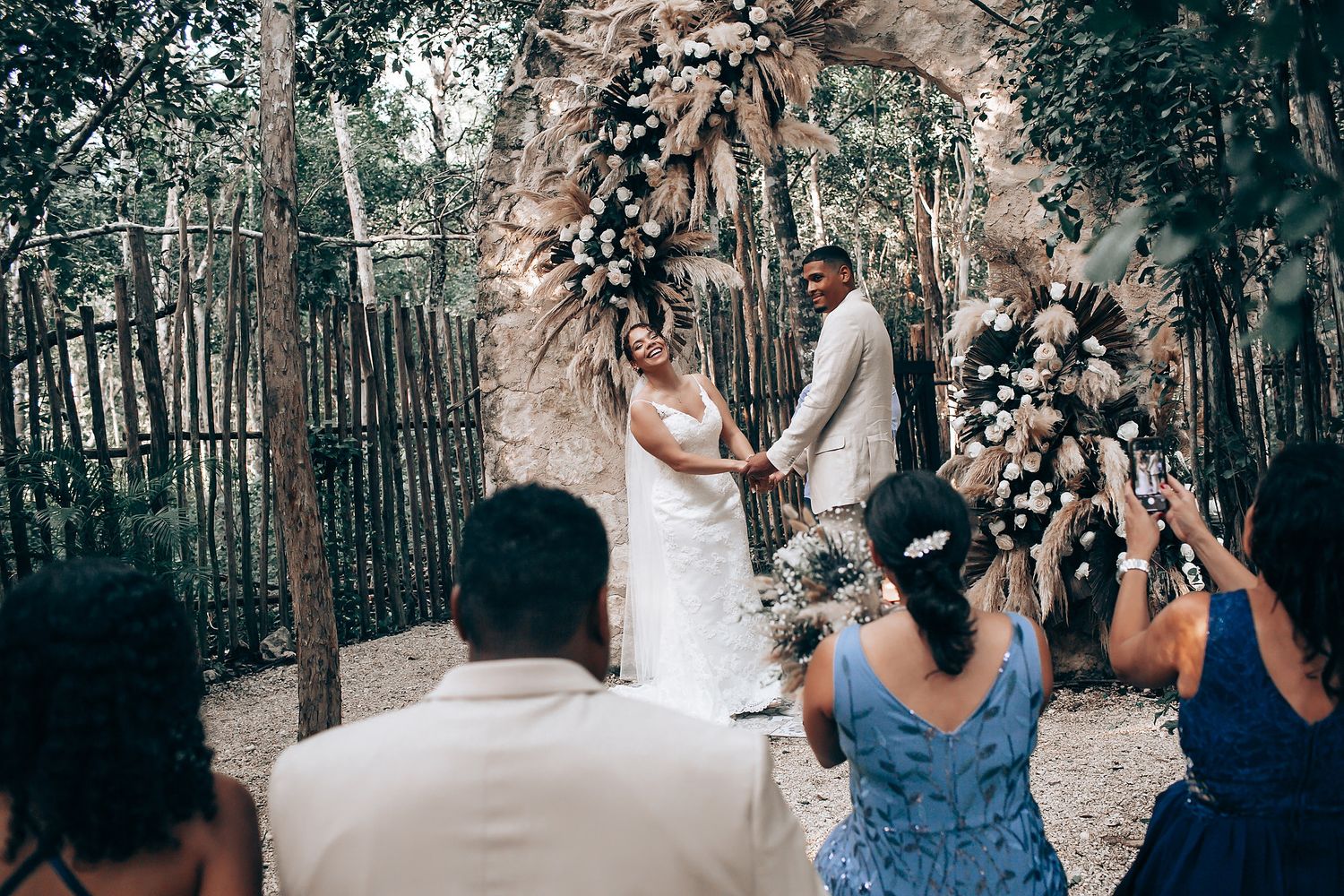 Wedding guests watching a ceremony in a rustic outdoor woodland venue.