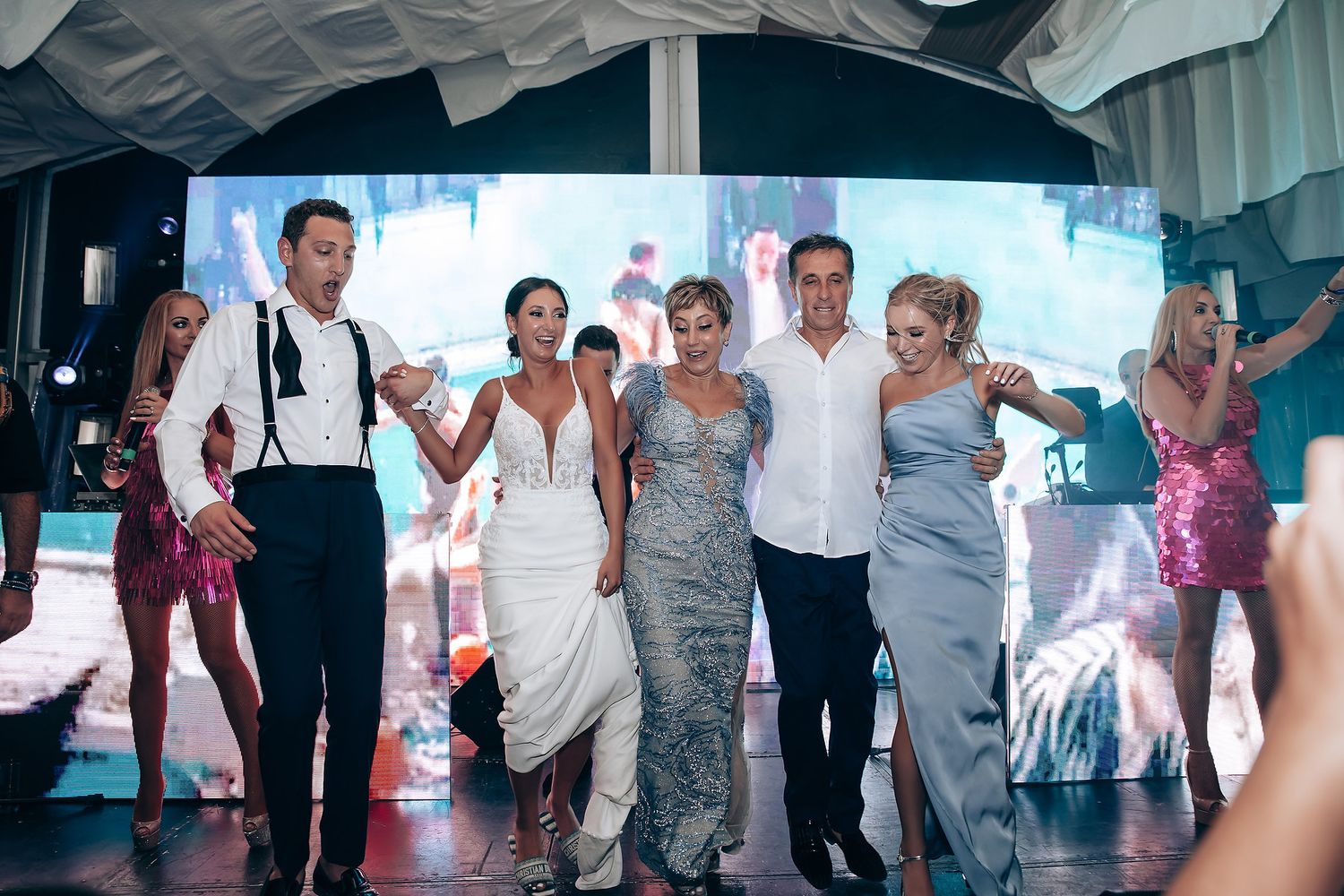 Wedding reception dance floor filled with guests celebrating under white draped ceiling decor.