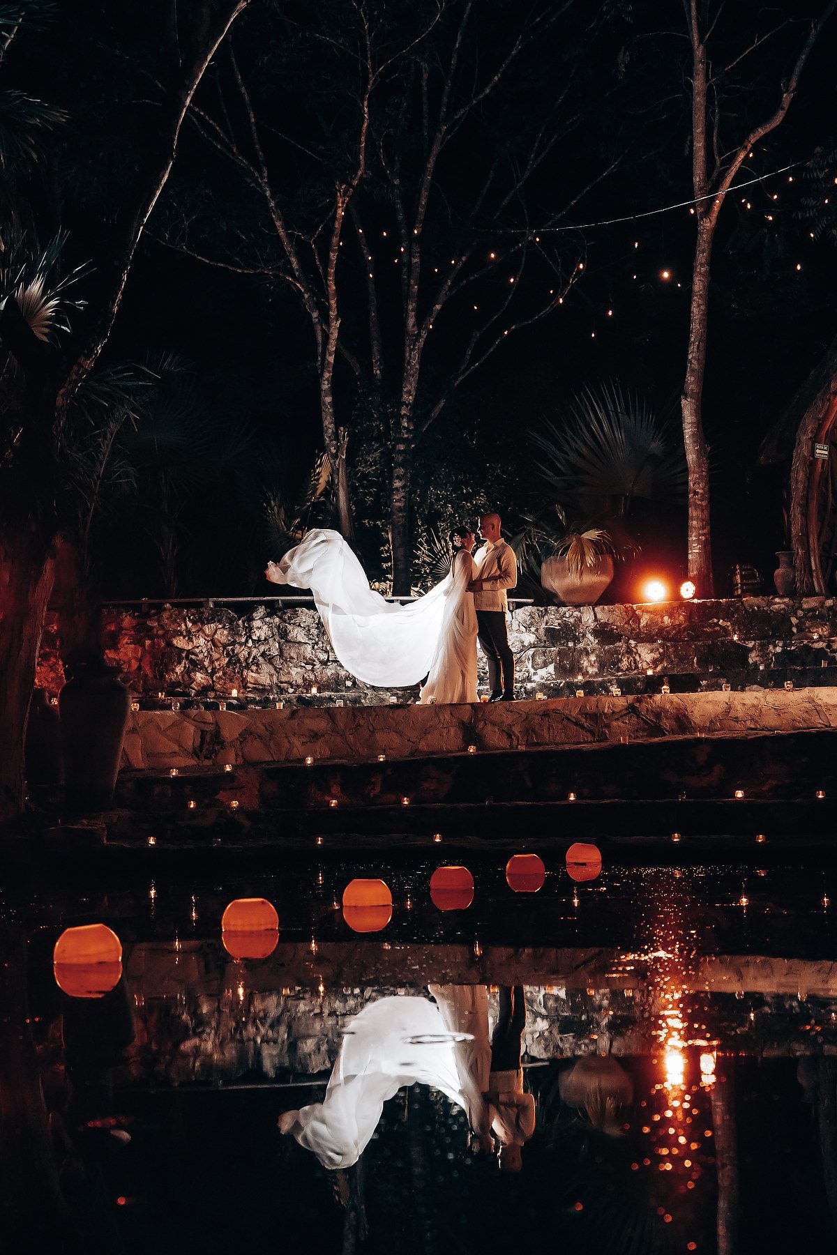 Paper lanterns illuminate a garden wall at night creating a magical atmosphere.