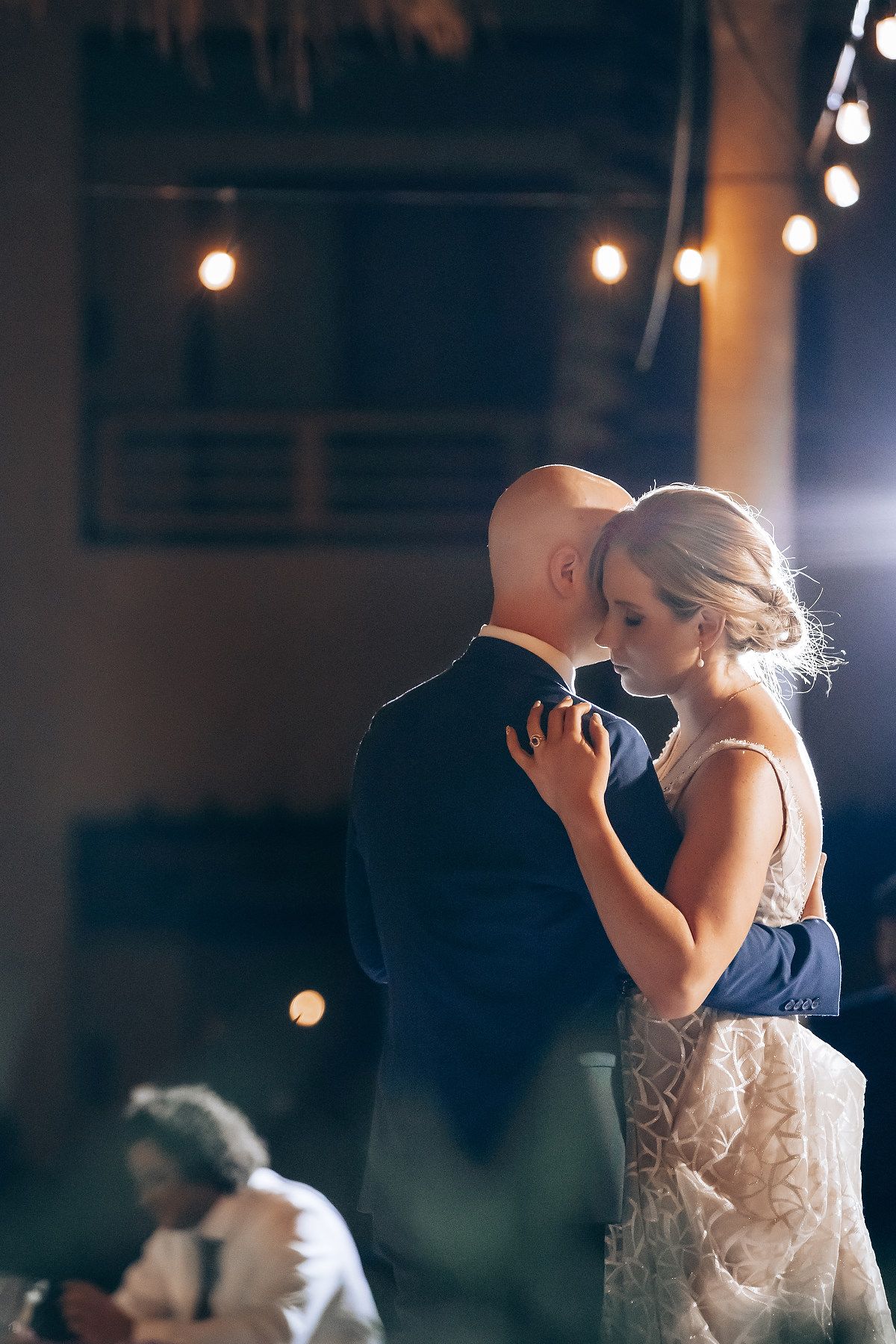A couple embracing and dancing at a wedding reception, with soft lighting and a romantic atmosphere.