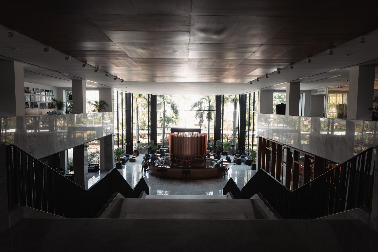 Grand modern library interior with sweeping staircase, glass railings, and illuminated bookshelves in an elegant atrium.