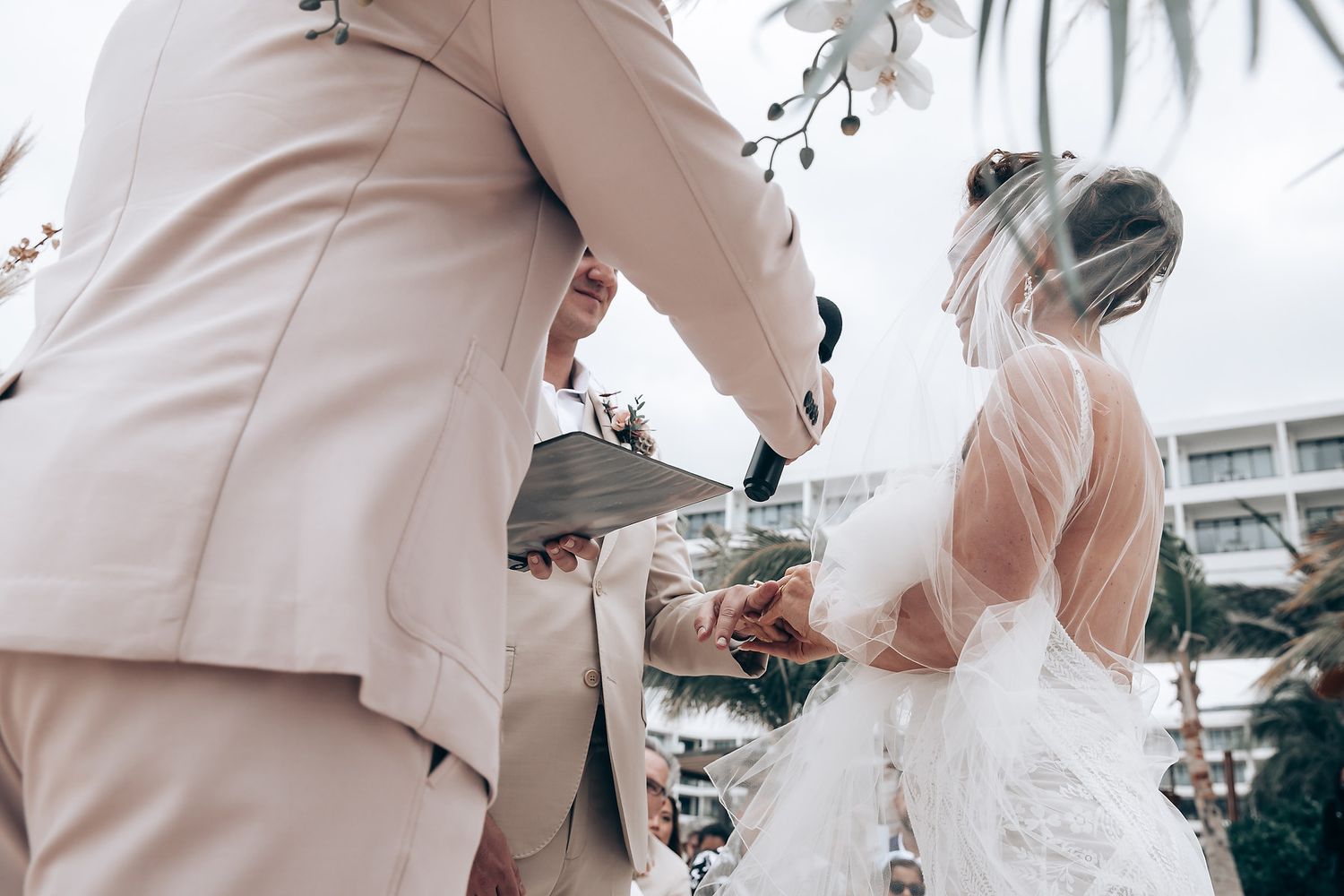 Wedding party members in beige suits stand together during beach celebration.