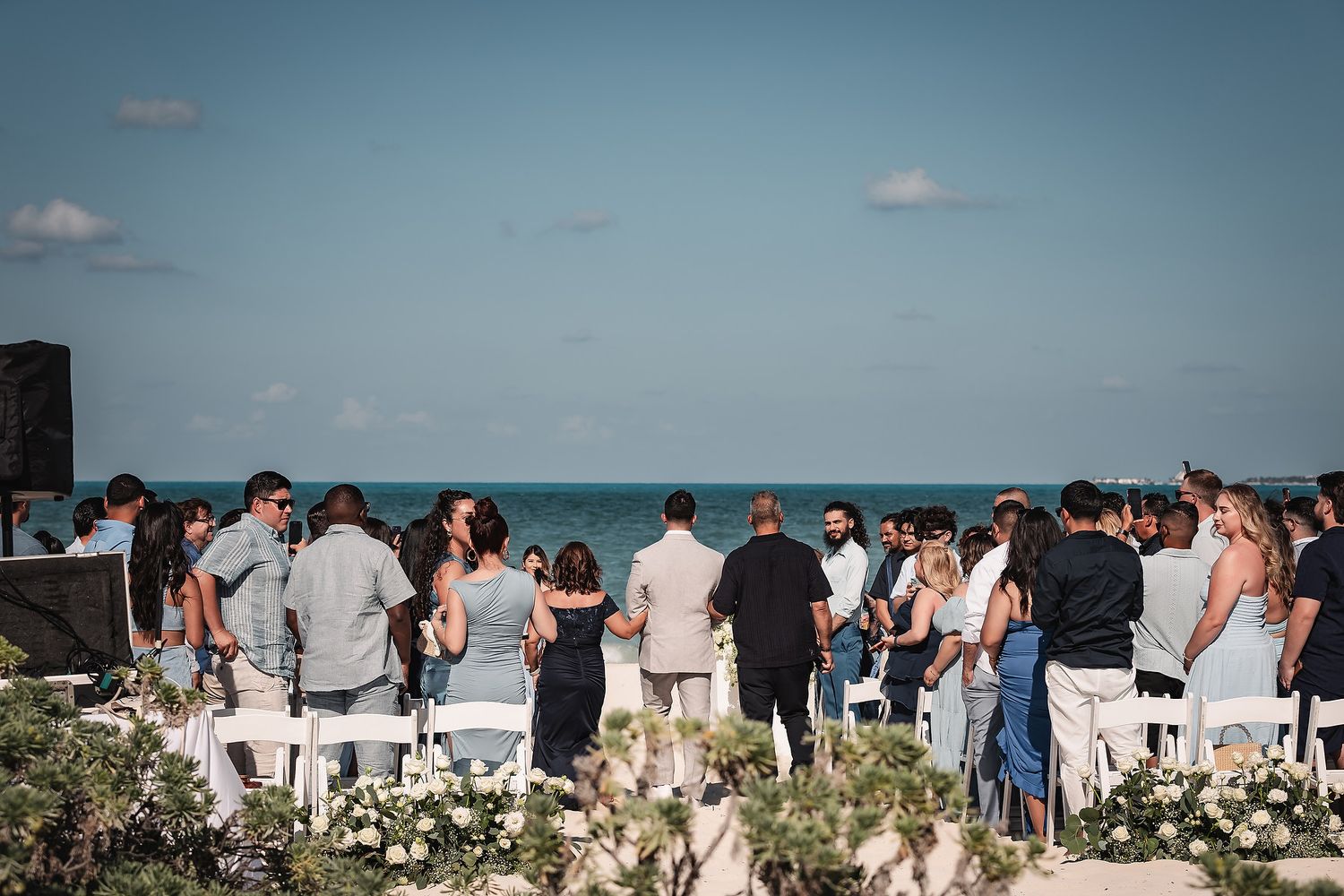 Guests gather for outdoor beach wedding ceremony with ocean view.