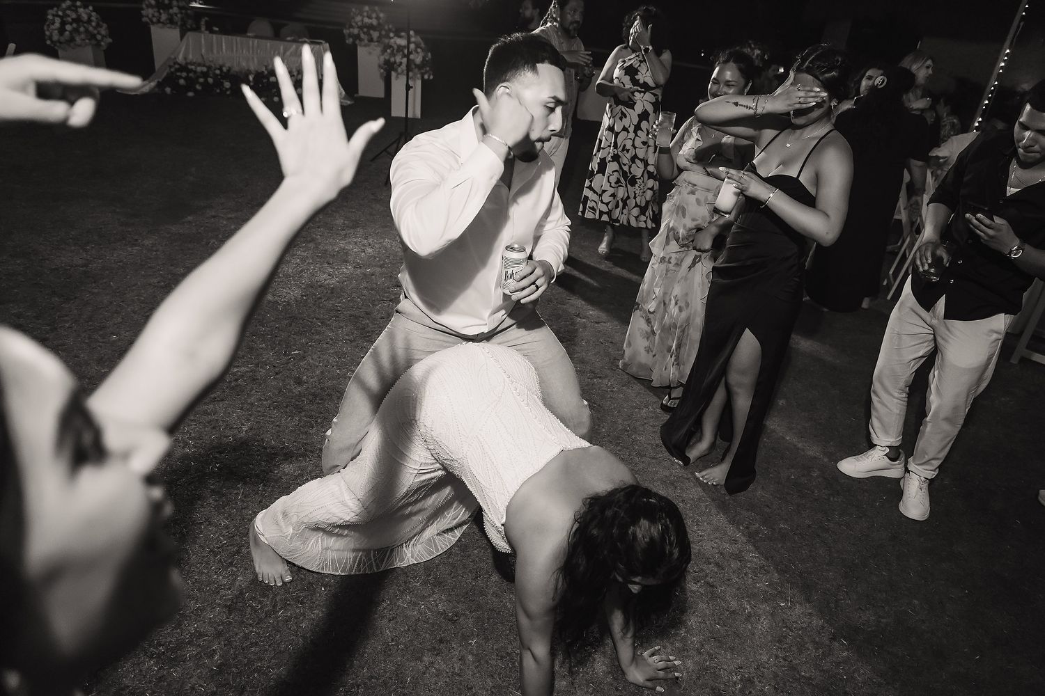 Wedding guests dancing energetically on outdoor dance floor during lively evening reception celebration.