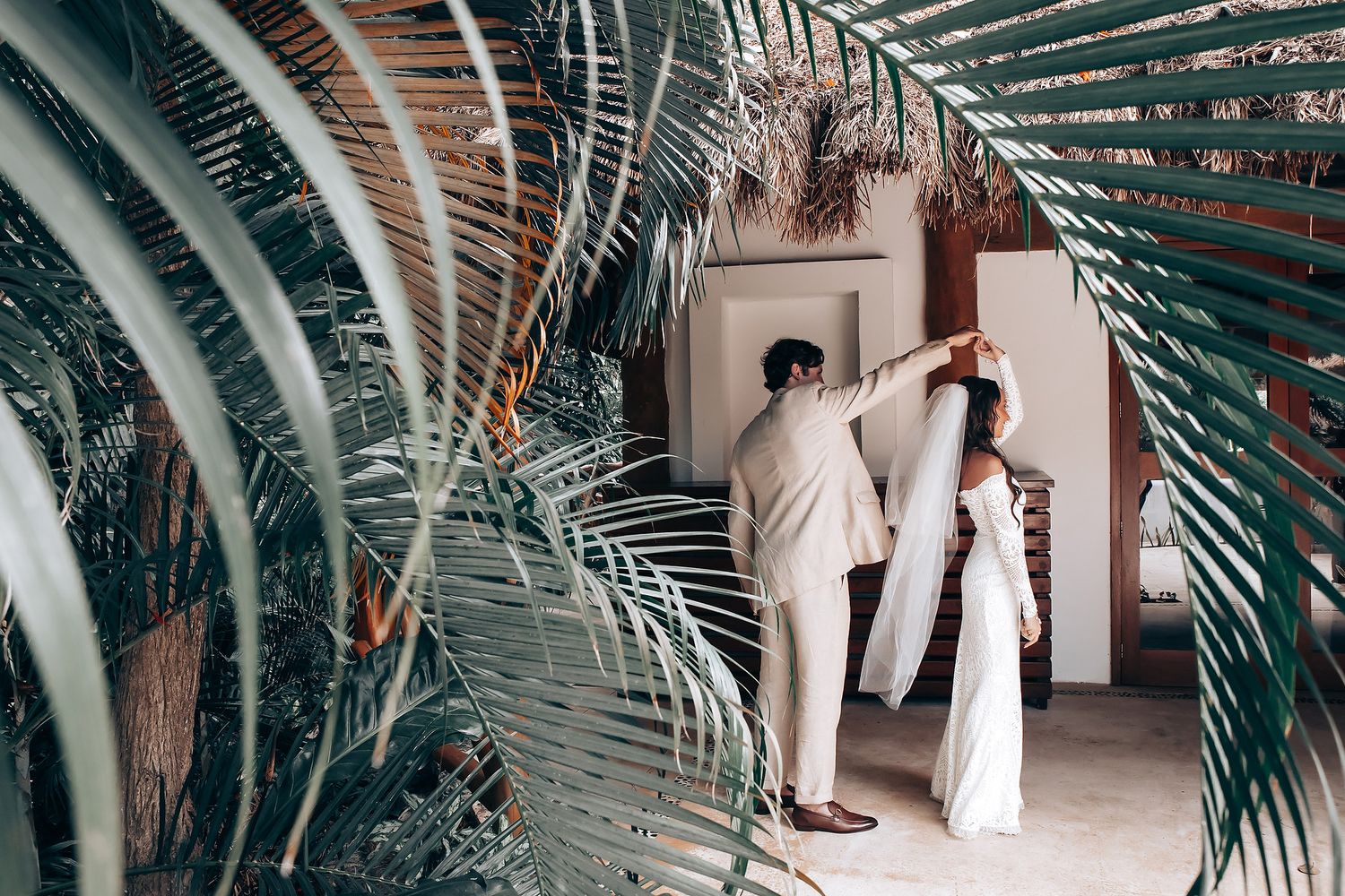 Palm fronds frame a walkway at a tropical wedding venue.