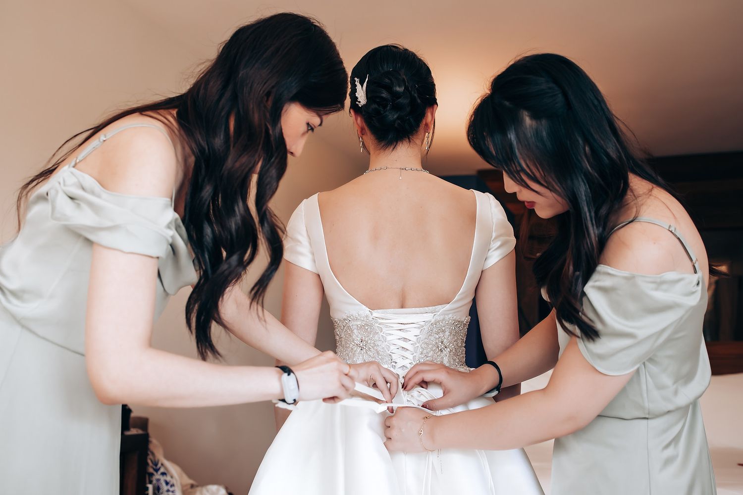 Wedding preparation scene showing details of a white bridal gown being adjusted.