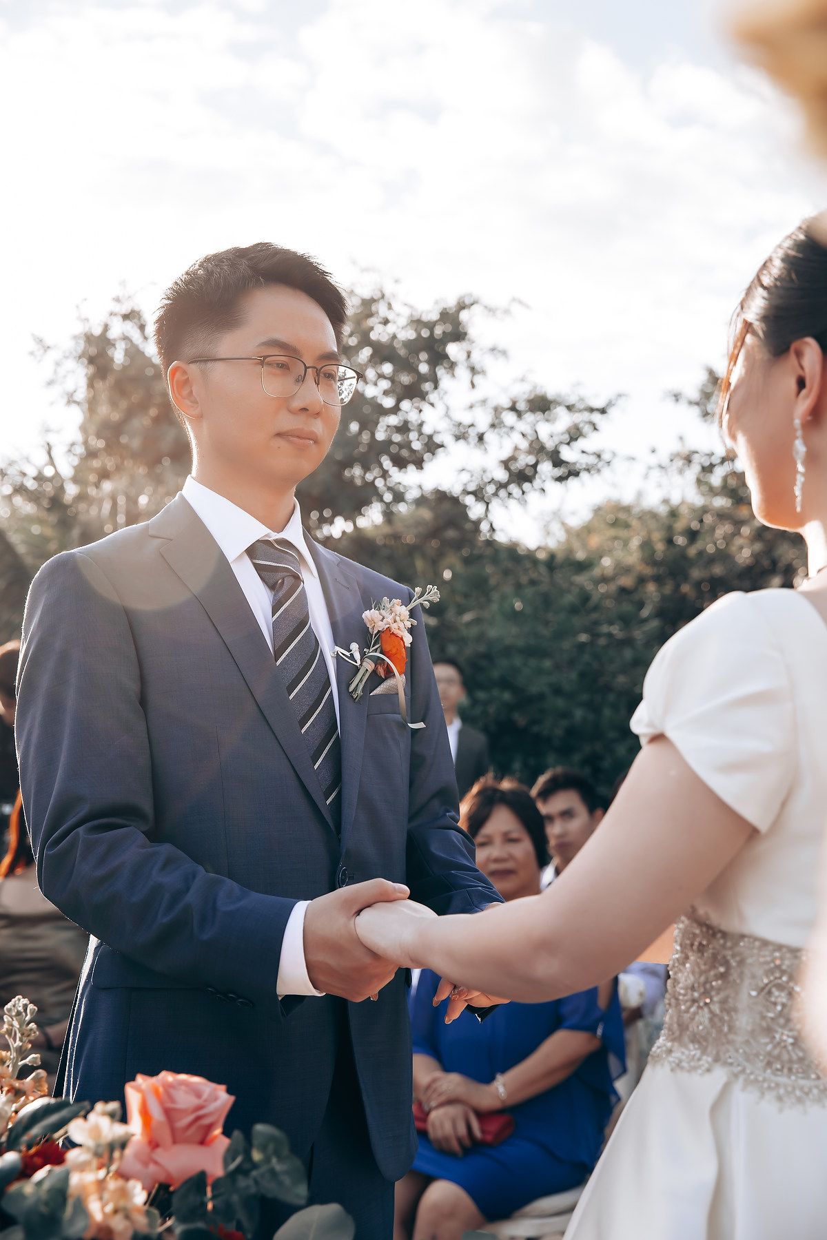 Outdoor wedding ceremony with guests gathered under natural lighting.
