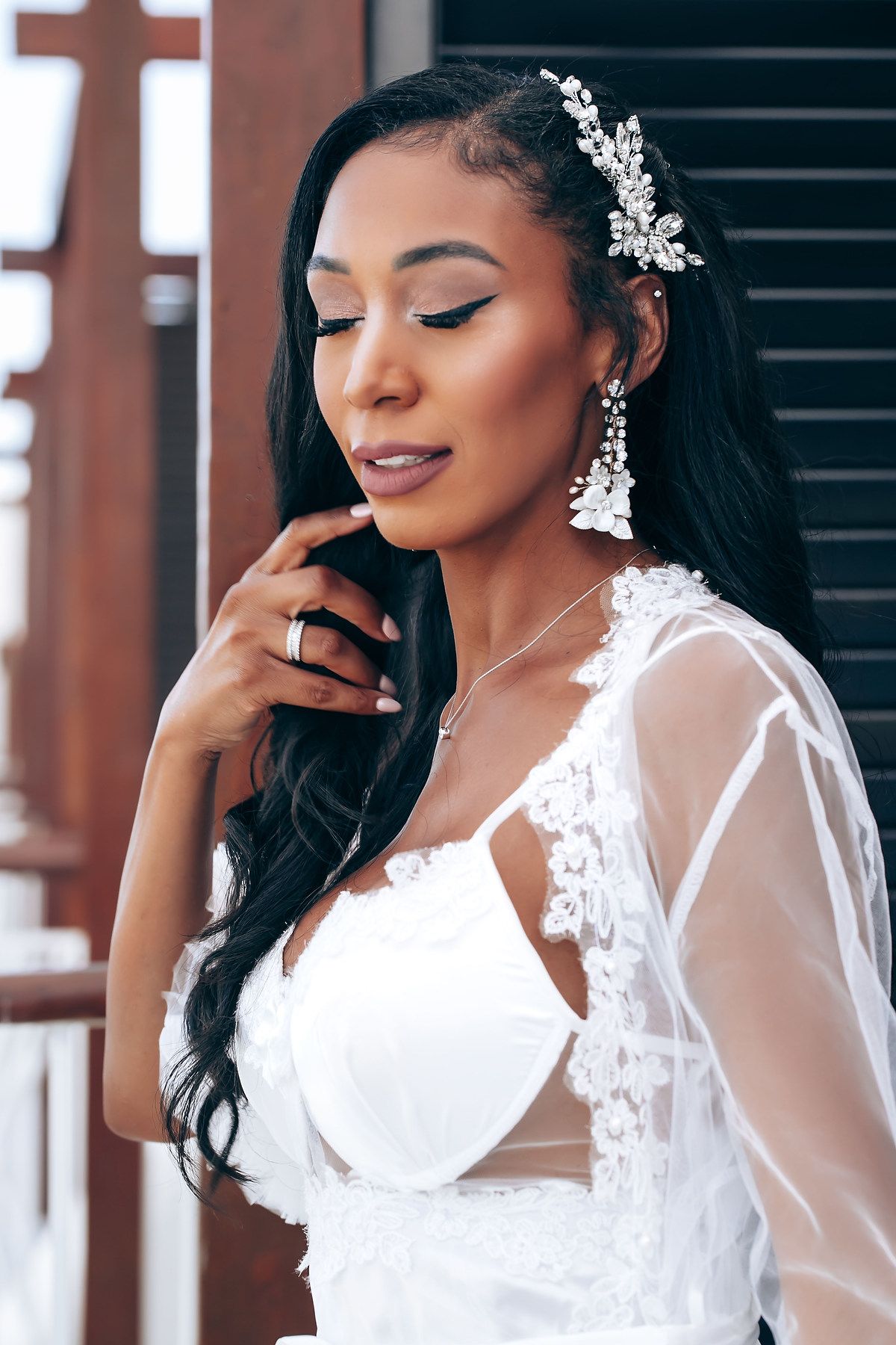 Bride in white lace dress and crystal hair accessories poses elegantly for bridal portraits.
