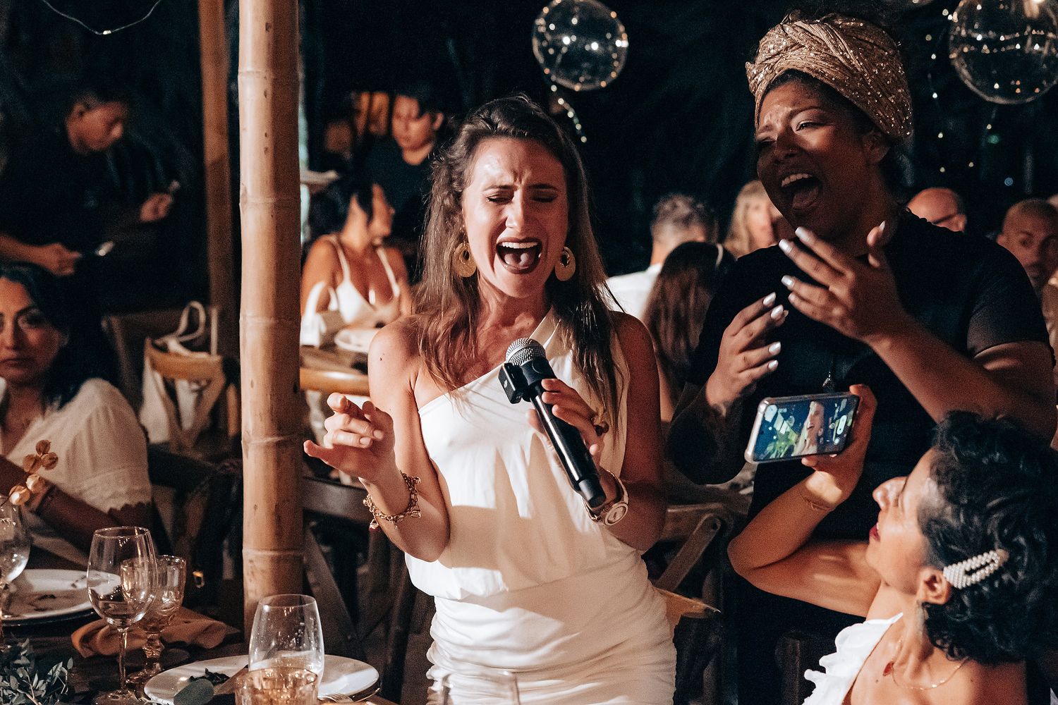 People laughing and socializing at a lively restaurant or bar gathering in a dimly lit setting.