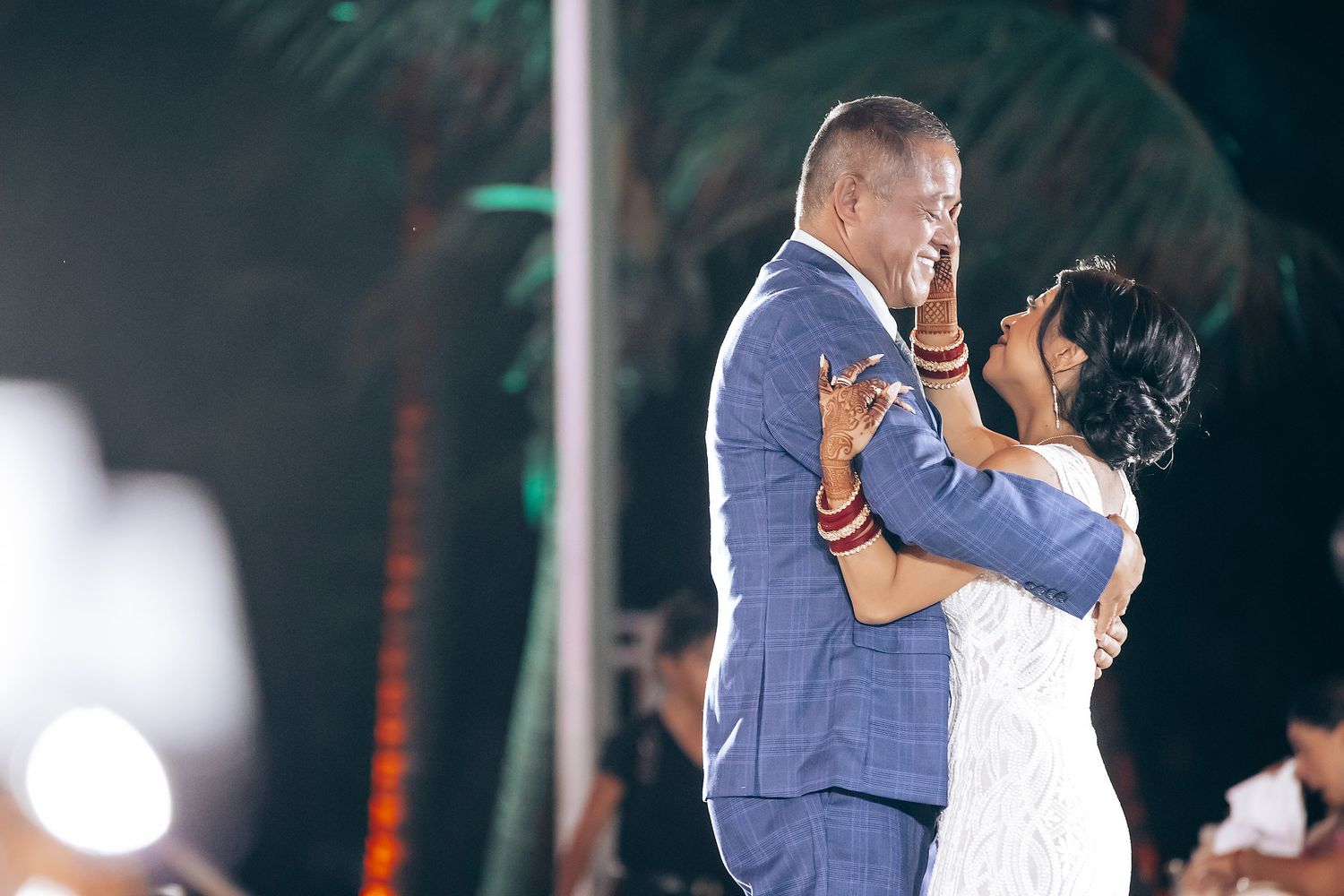 Wedding couple dancing together under dramatic lighting and chandeliers.