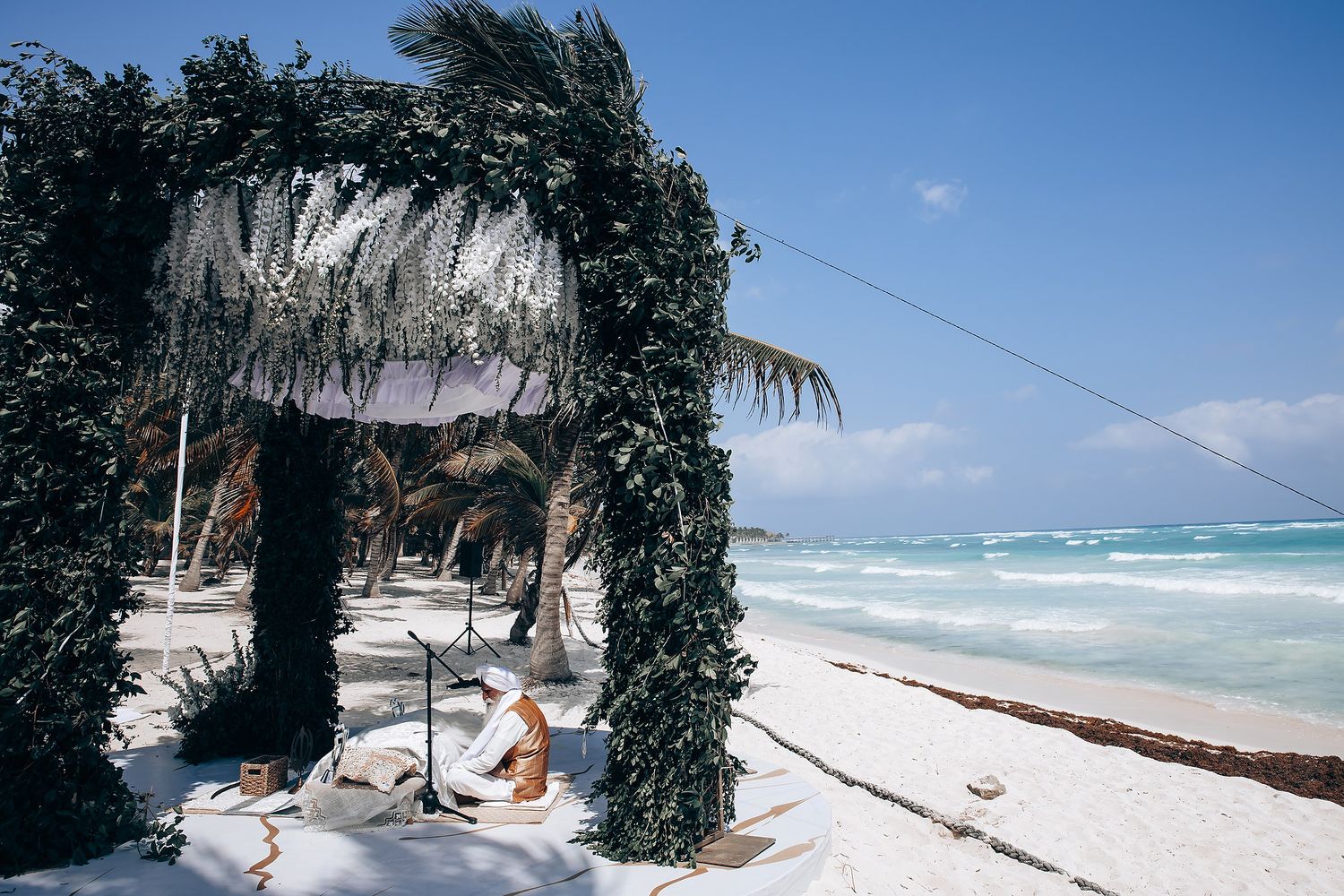 Turquoise ocean waves meet white sandy beach lined with swaying palm trees.