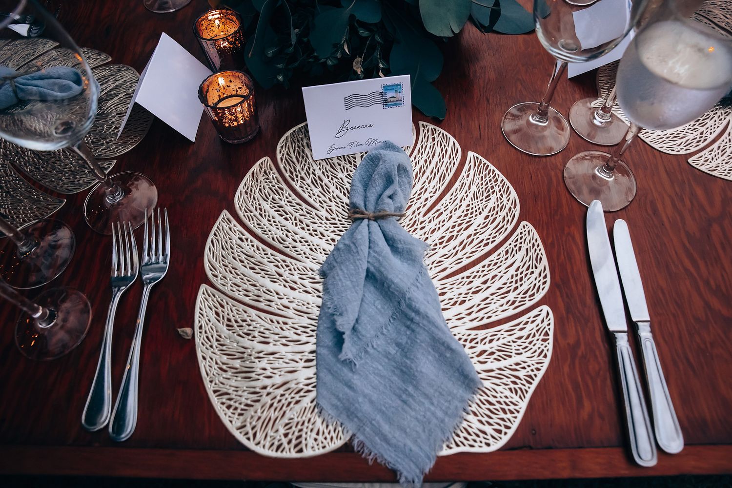 Elegant table settings with white charger plates and gray napkins at a formal reception.