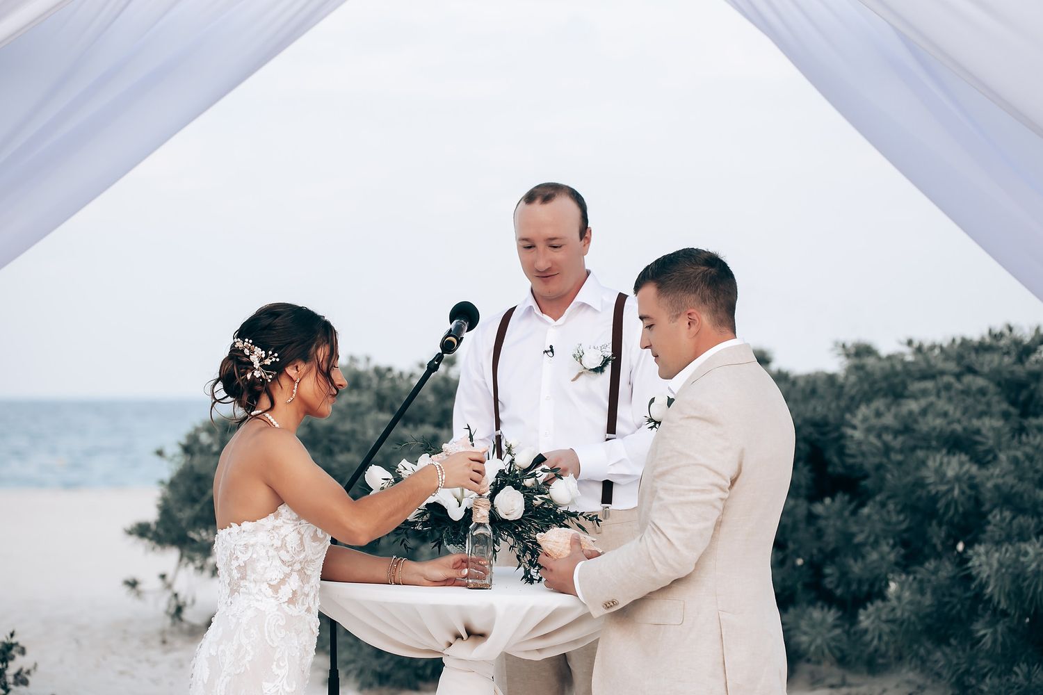 Wedding couple shares intimate moments on a scenic beach with white sand and ocean views during their tropical ceremony.