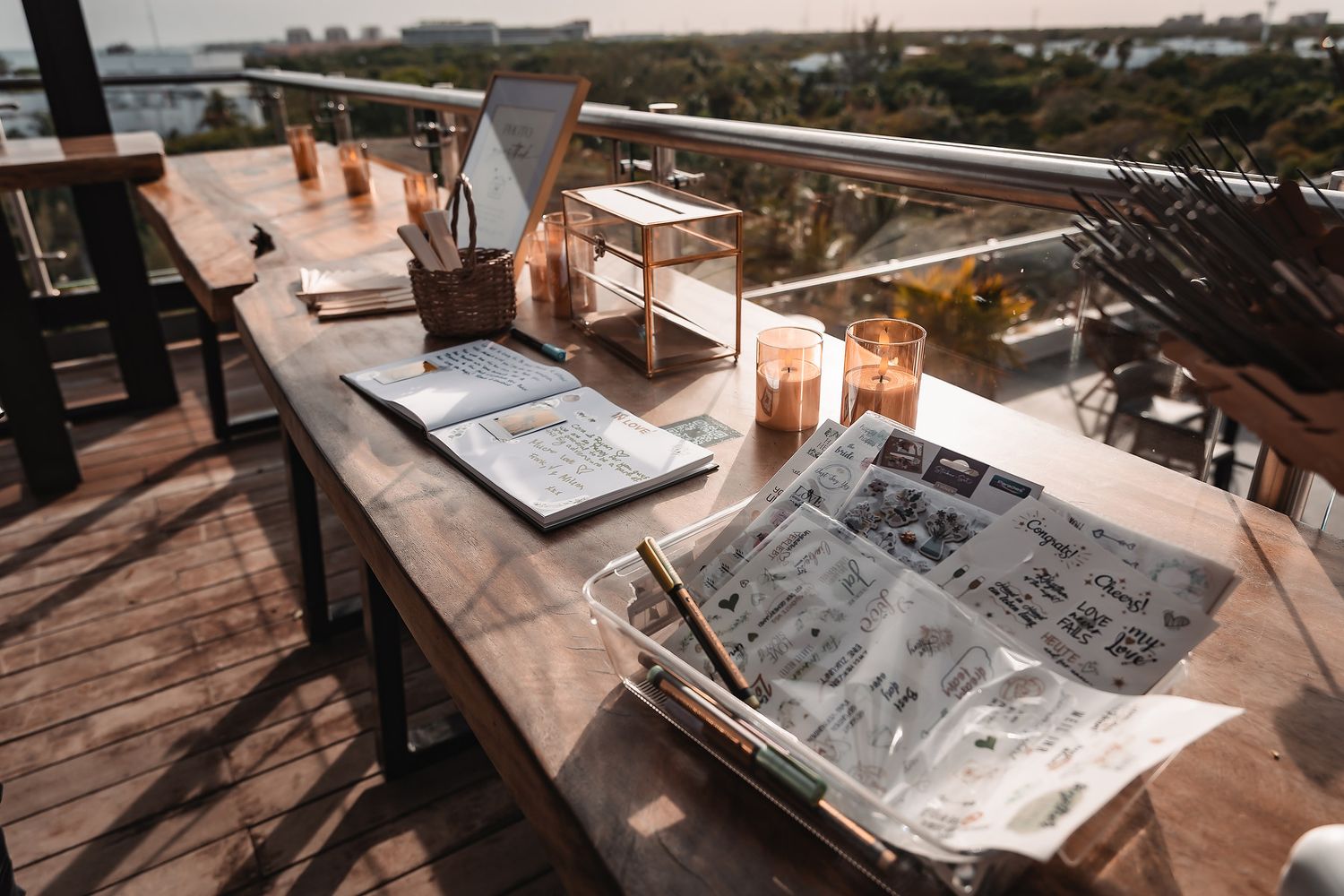 Wedding planning materials and papers laid out on rustic wooden table at sunset.