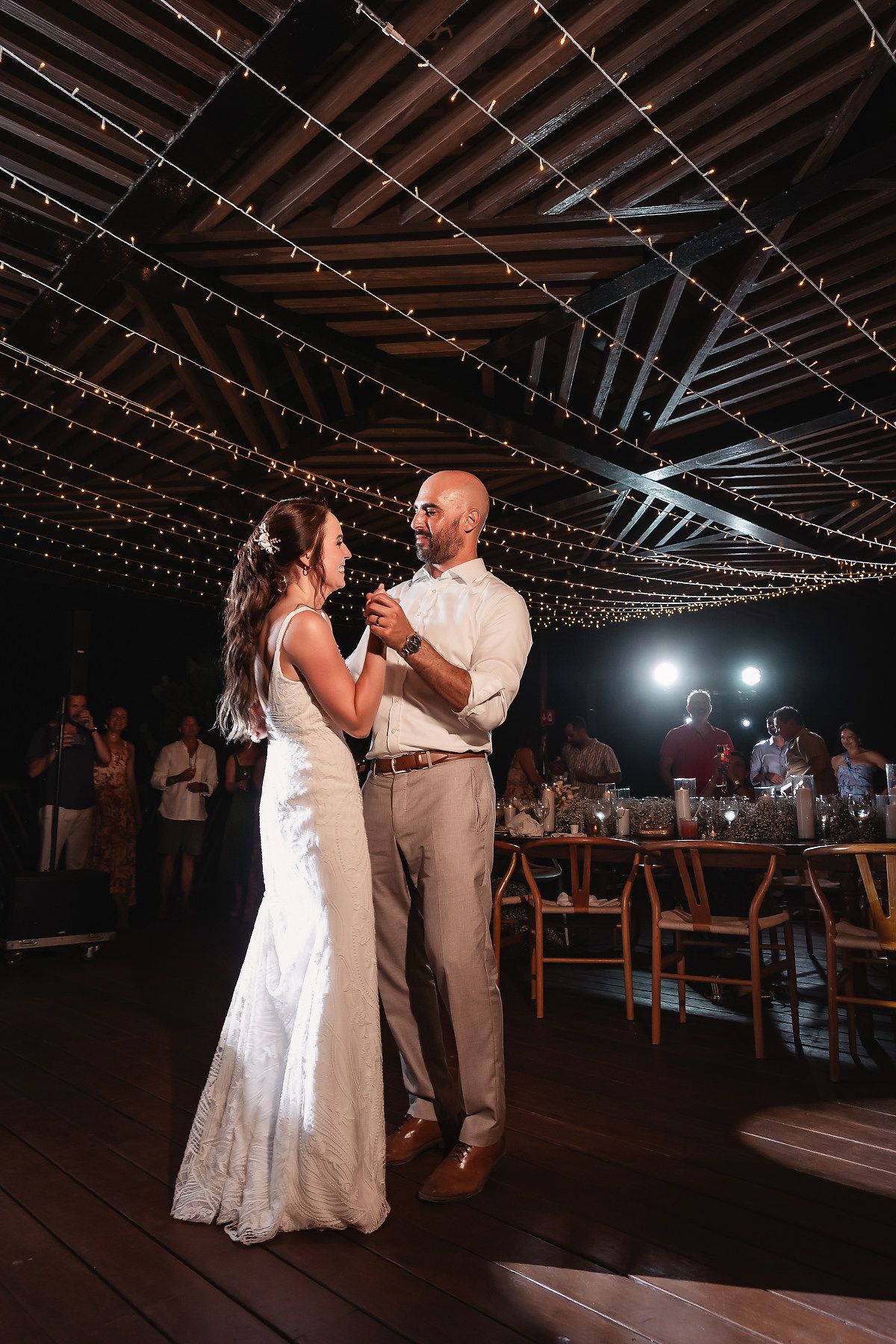 Wedding reception first dance under twinkling lights in rustic venue.