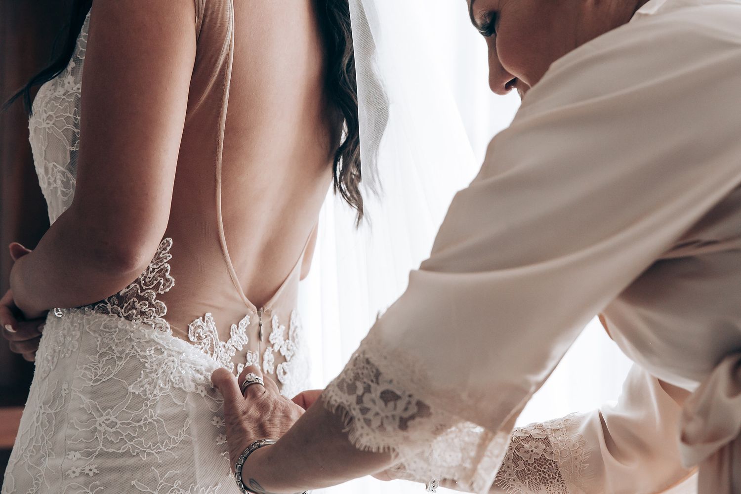 A close-up detail shot of a white wedding dress with delicate lace and beading details.
