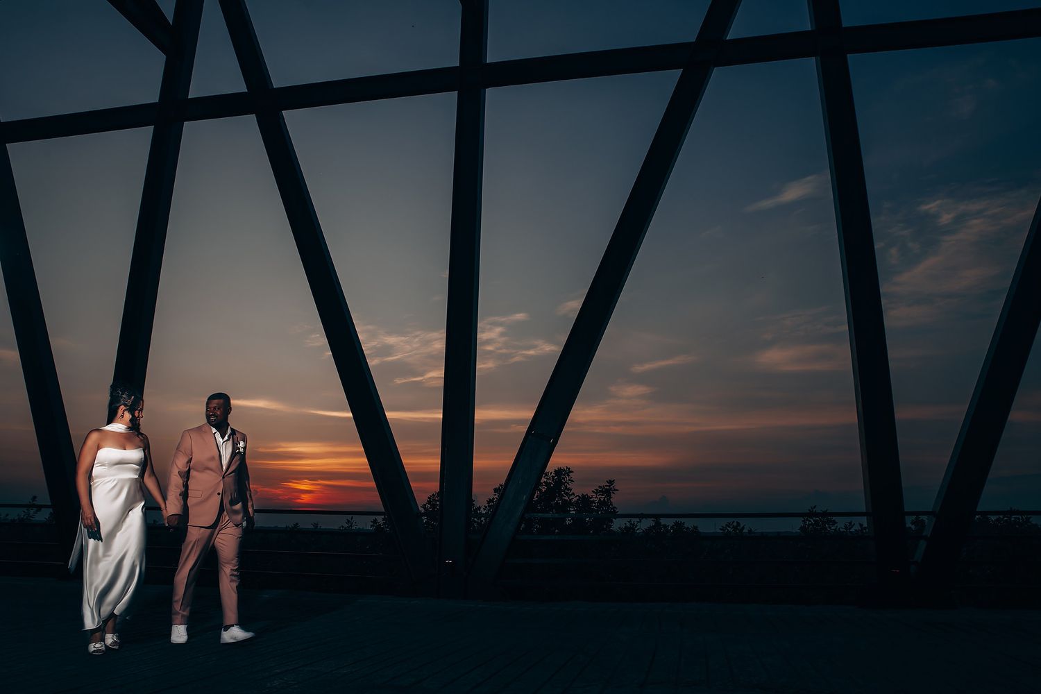 Silhouettes against dramatic sunset sky framed by architectural elements.