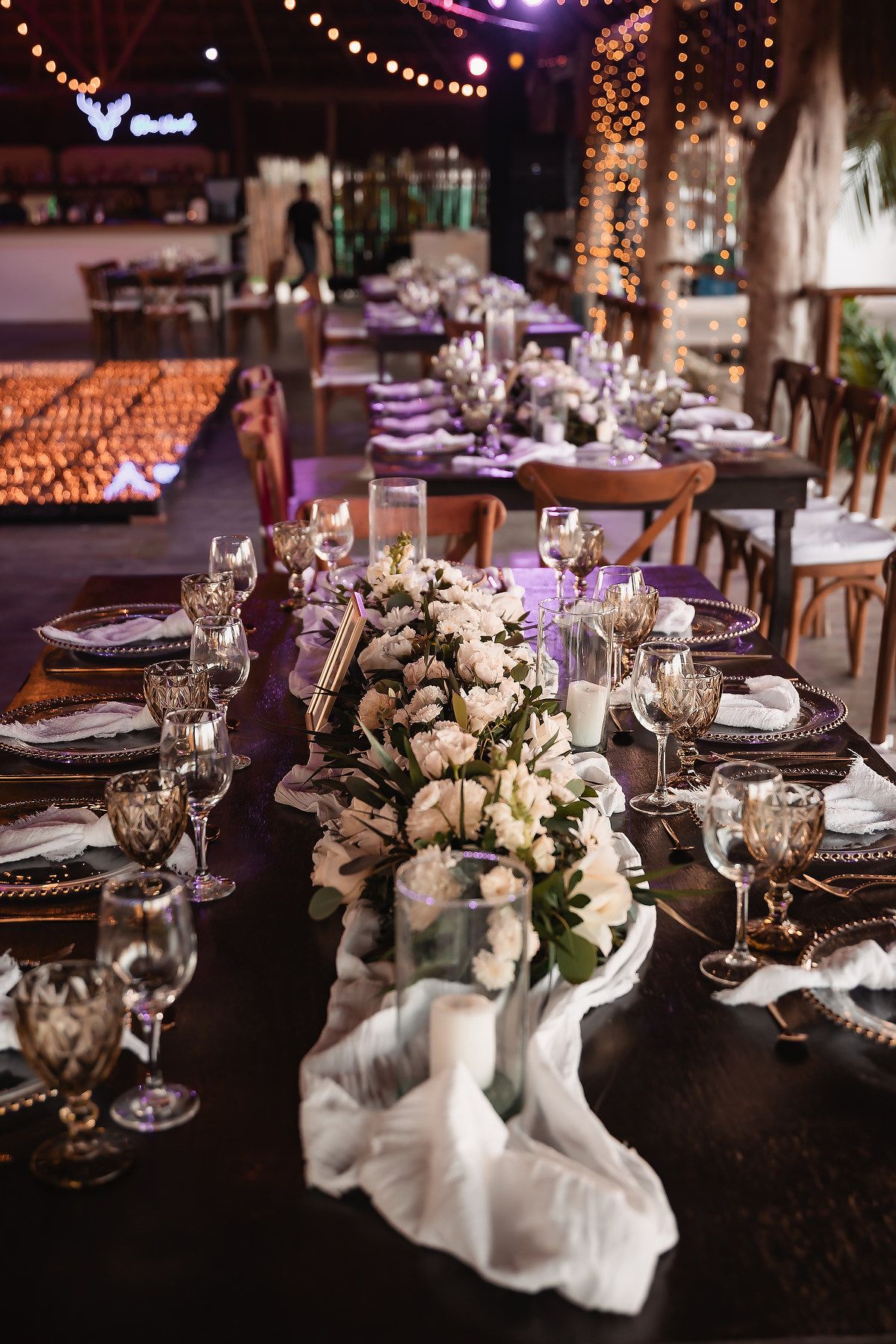 Elegant wedding reception table settings with white floral centerpieces and wine glasses.