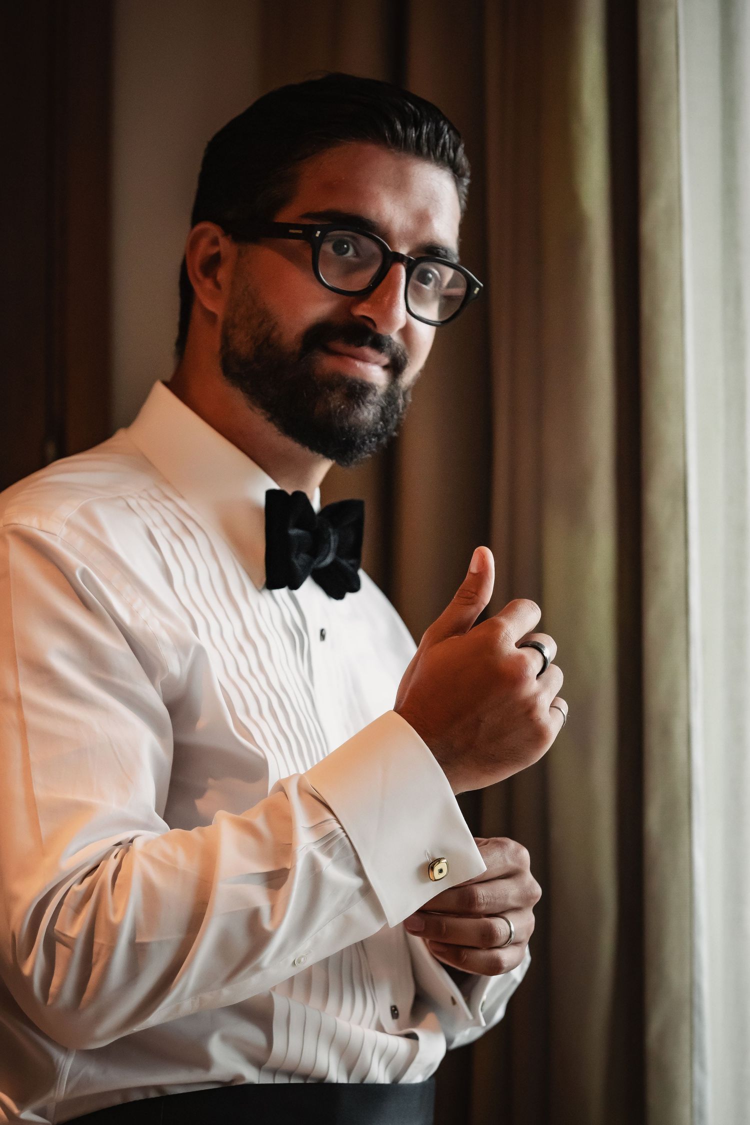 Close-up shots of a groom in glasses and bow tie preparing for his wedding day.