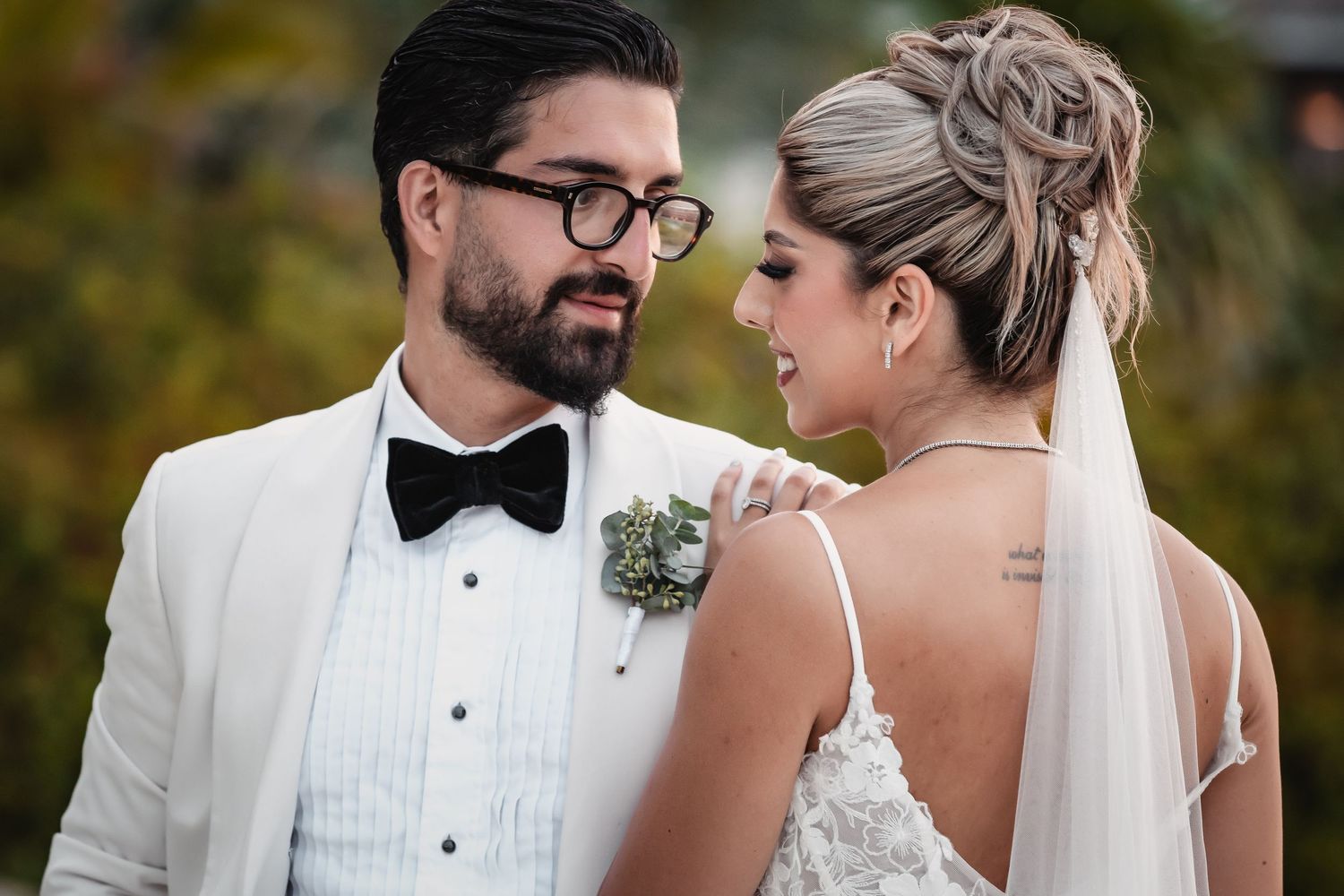 Elegant couple in formal wedding attire share a tender moment outdoors.