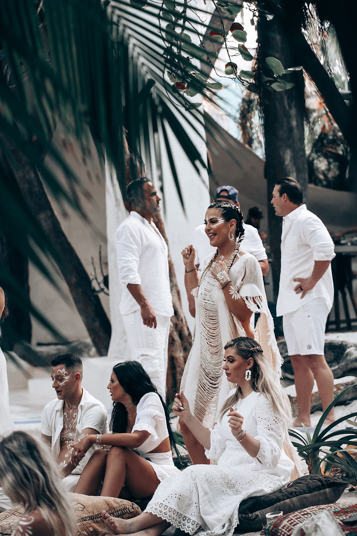 Group enjoying a casual beach gathering in white and casual summer clothing.