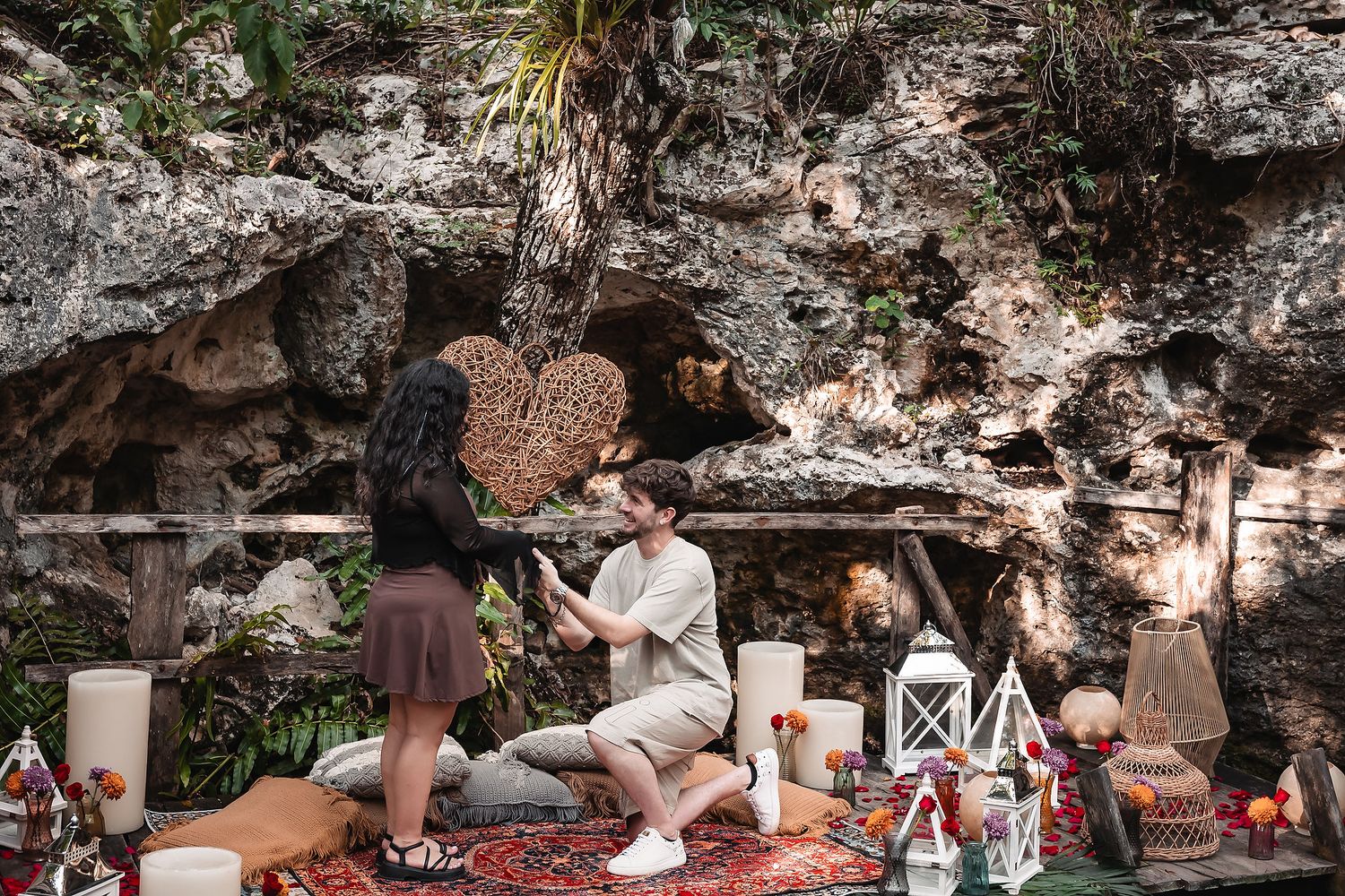 Romantic moment captured at a decorated cenote setting with lanterns and rugs.