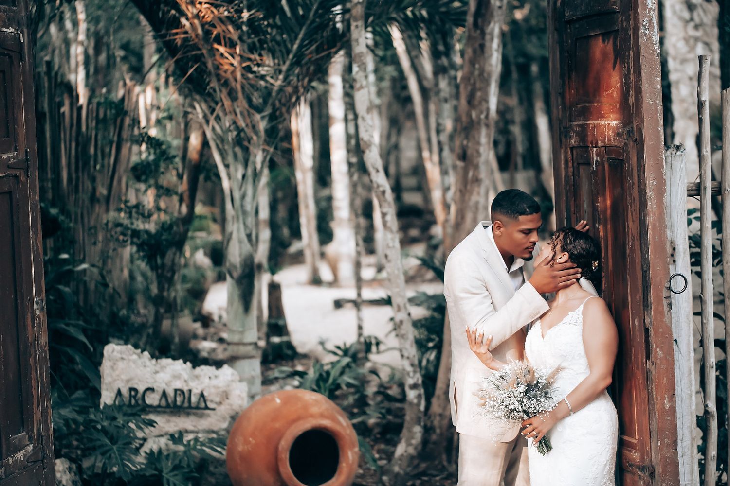 A couple embraces during their wedding celebration in front of a rustic wooden structure.