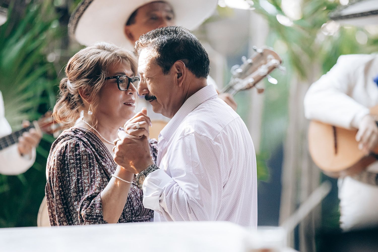 A couple shares an intimate moment among tropical greenery and natural light.