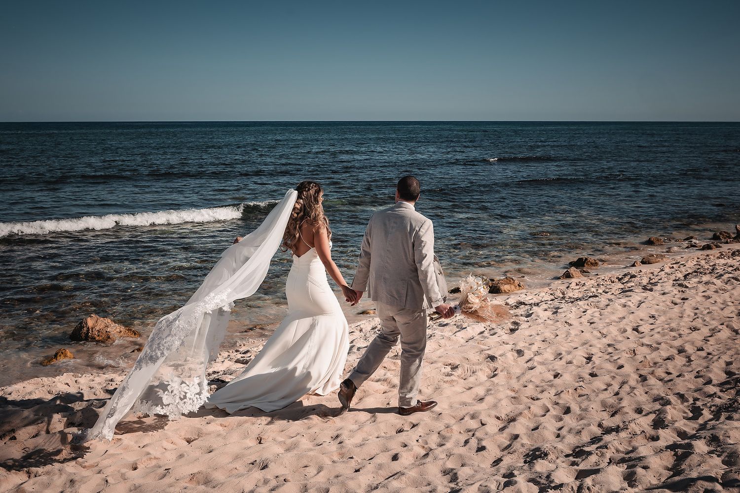 Wedding photography session on a scenic beach with ocean waves and sandy coastline.