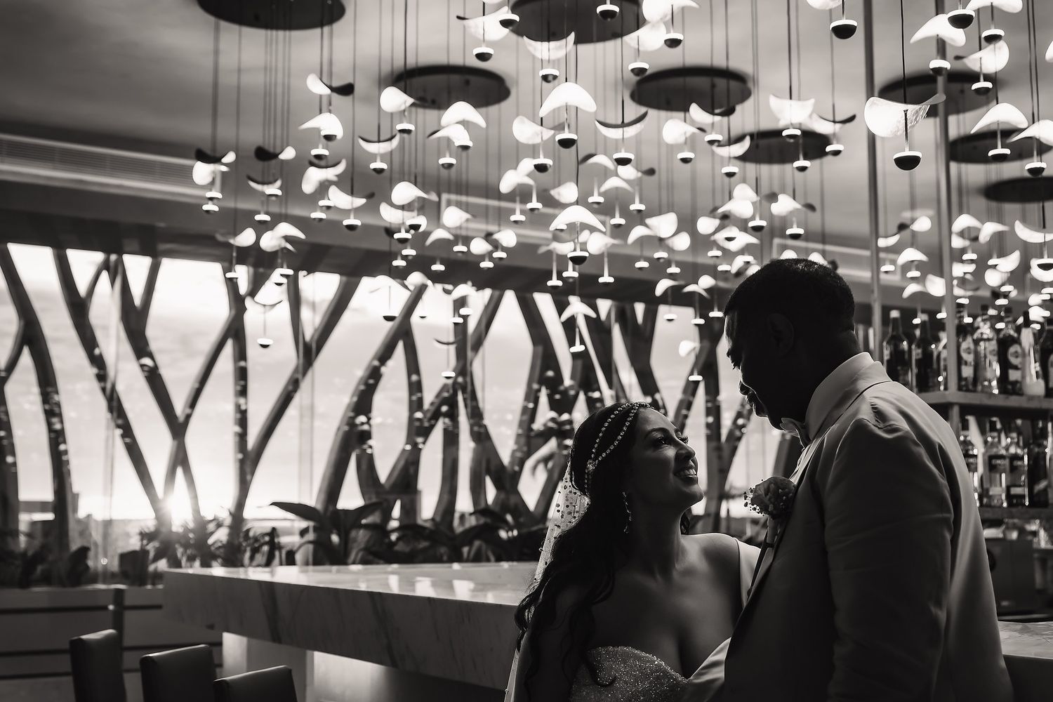 Black and white photo of elegant reception space with dramatic pendant lighting.