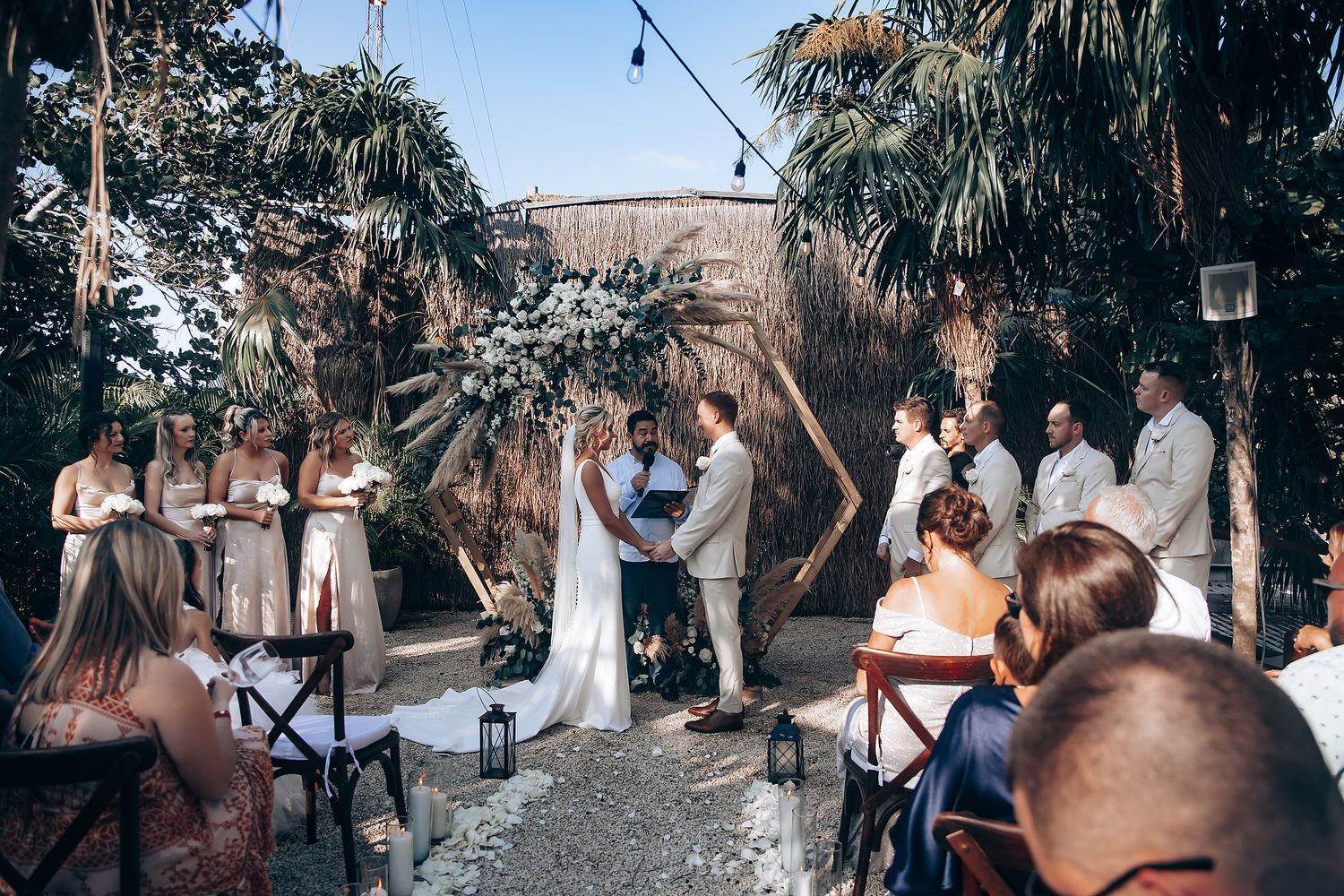 Rustic outdoor wedding venue with string lights and palm trees creating a natural ambiance.