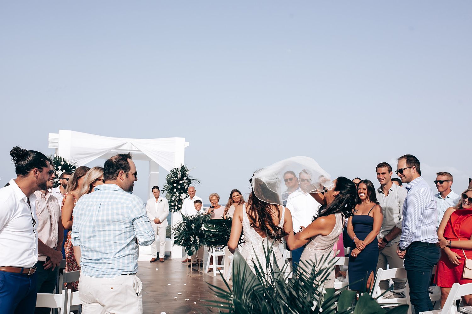 Outdoor wedding ceremony in progress with guests seated facing the ocean view.