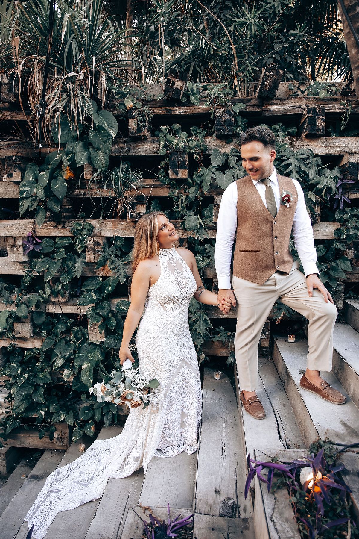 Couple shares intimate moments on wooden garden steps during their wedding celebration.