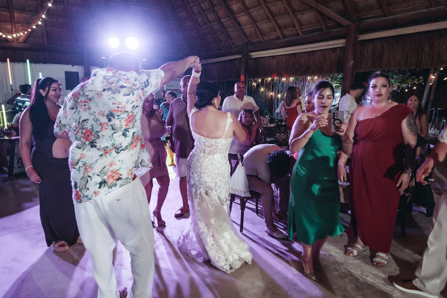 Bride and guests dancing joyfully at an outdoor wedding reception in a rustic venue.