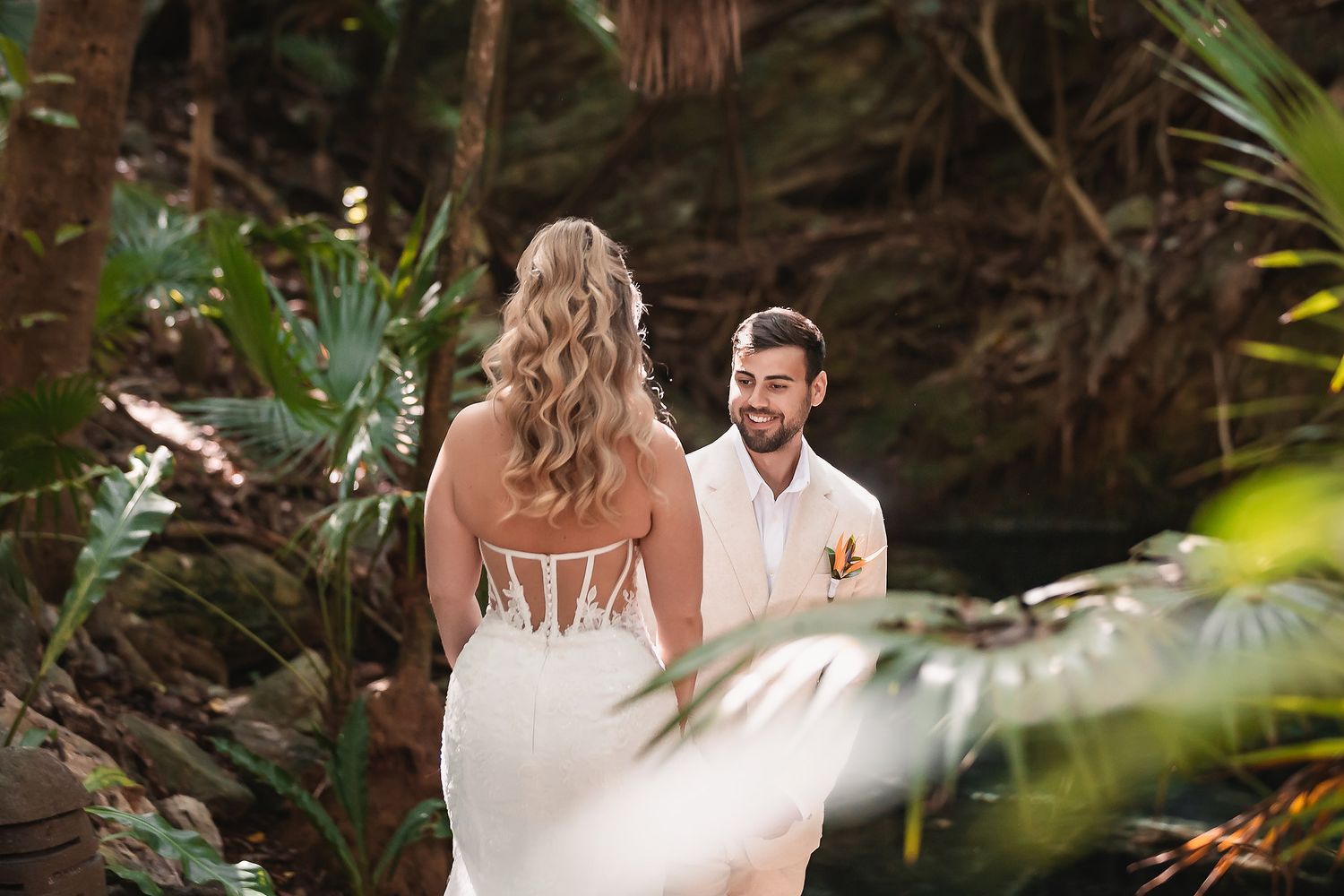 Bride and groom exchange vows in a lush tropical jungle setting, surrounded by green palms.