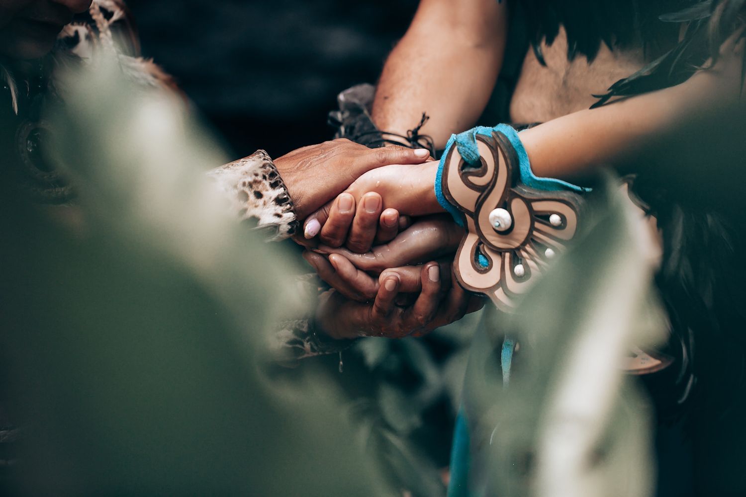 Close-up of hands joined together adorned with traditional Mayan bracelets and jewelry.