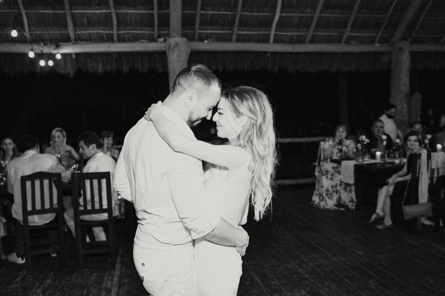 Black and white photo of bride and groom sharing an intimate first dance at a tropical wedding reception.