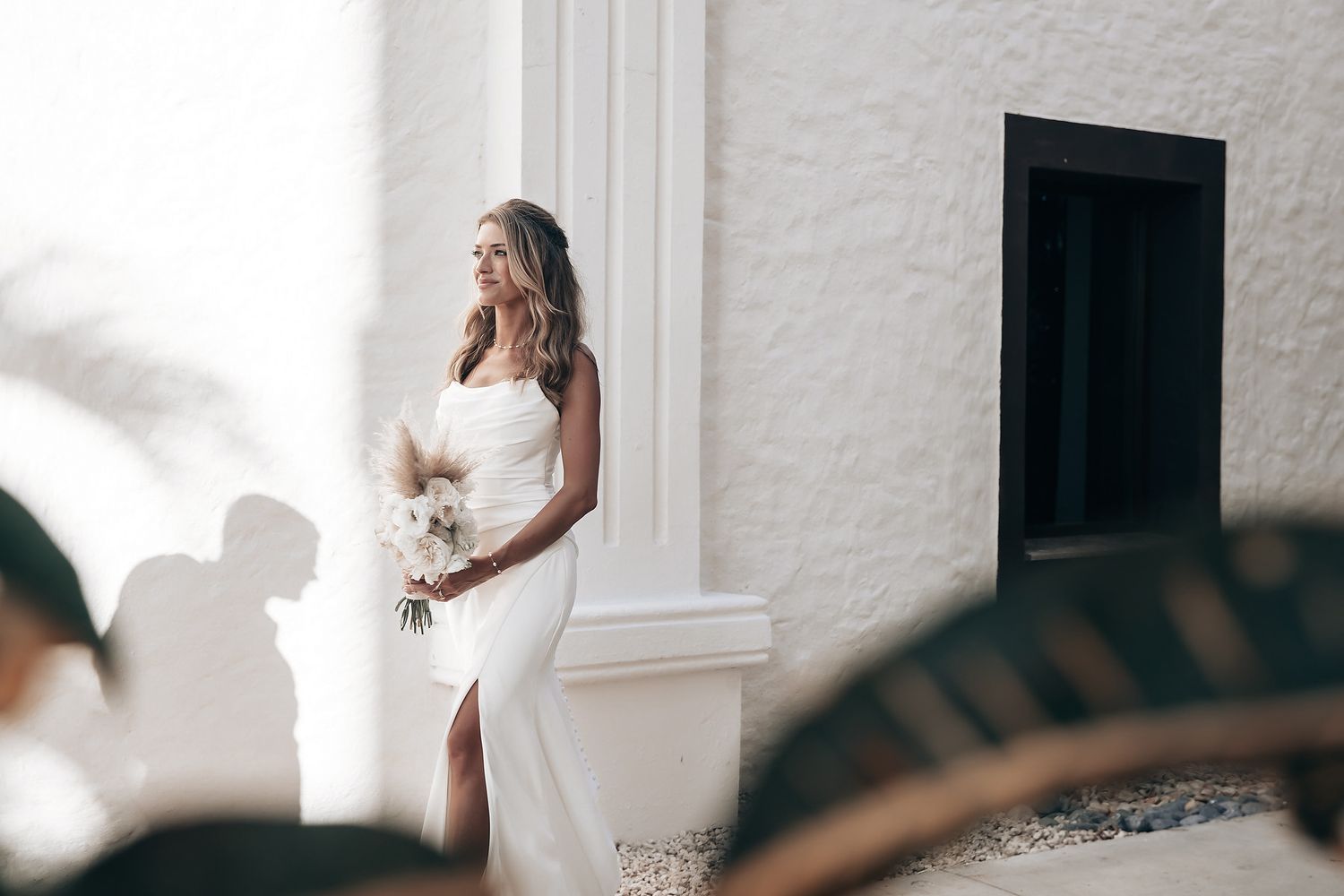 A bride in a white dress stands alone, surrounded by wedding guests.