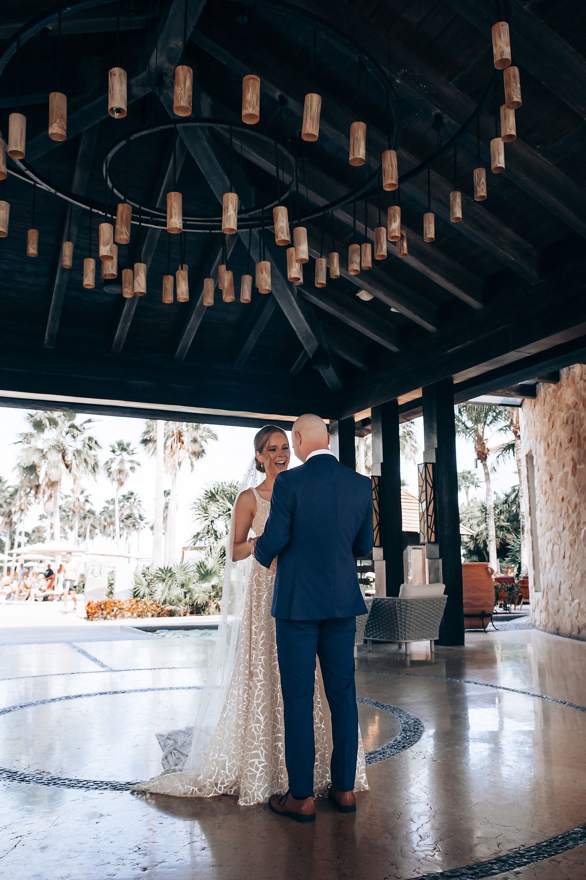 A bride and groom stand together in a covered outdoor venue with hanging lights.
