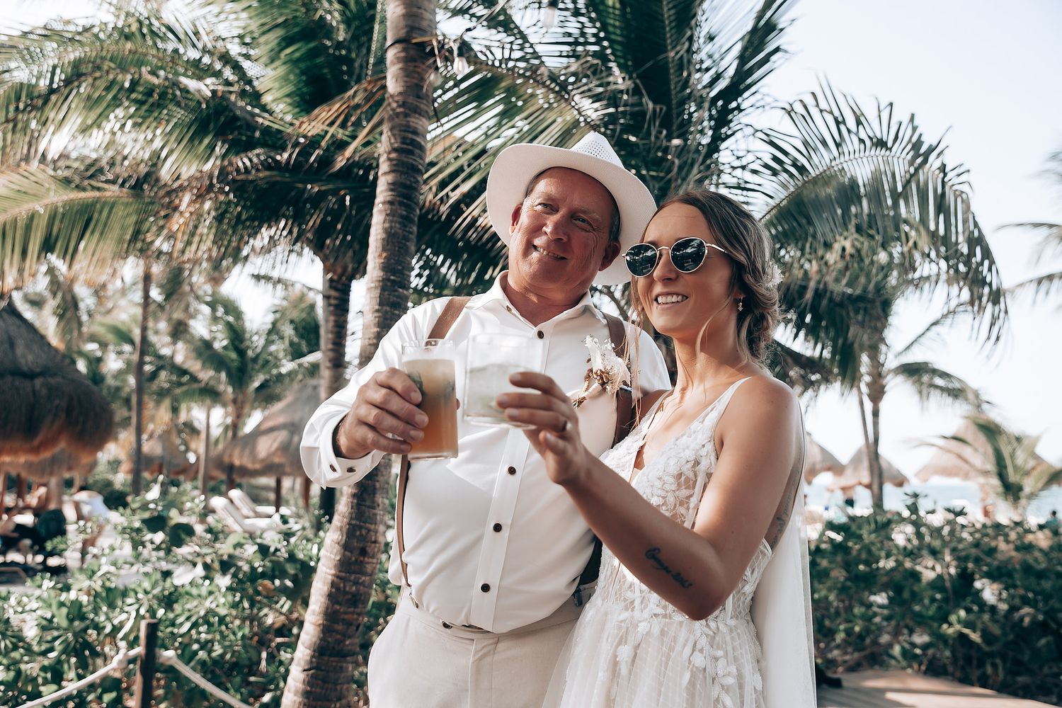 Couple enjoying tropical drinks at beachside wedding celebration.