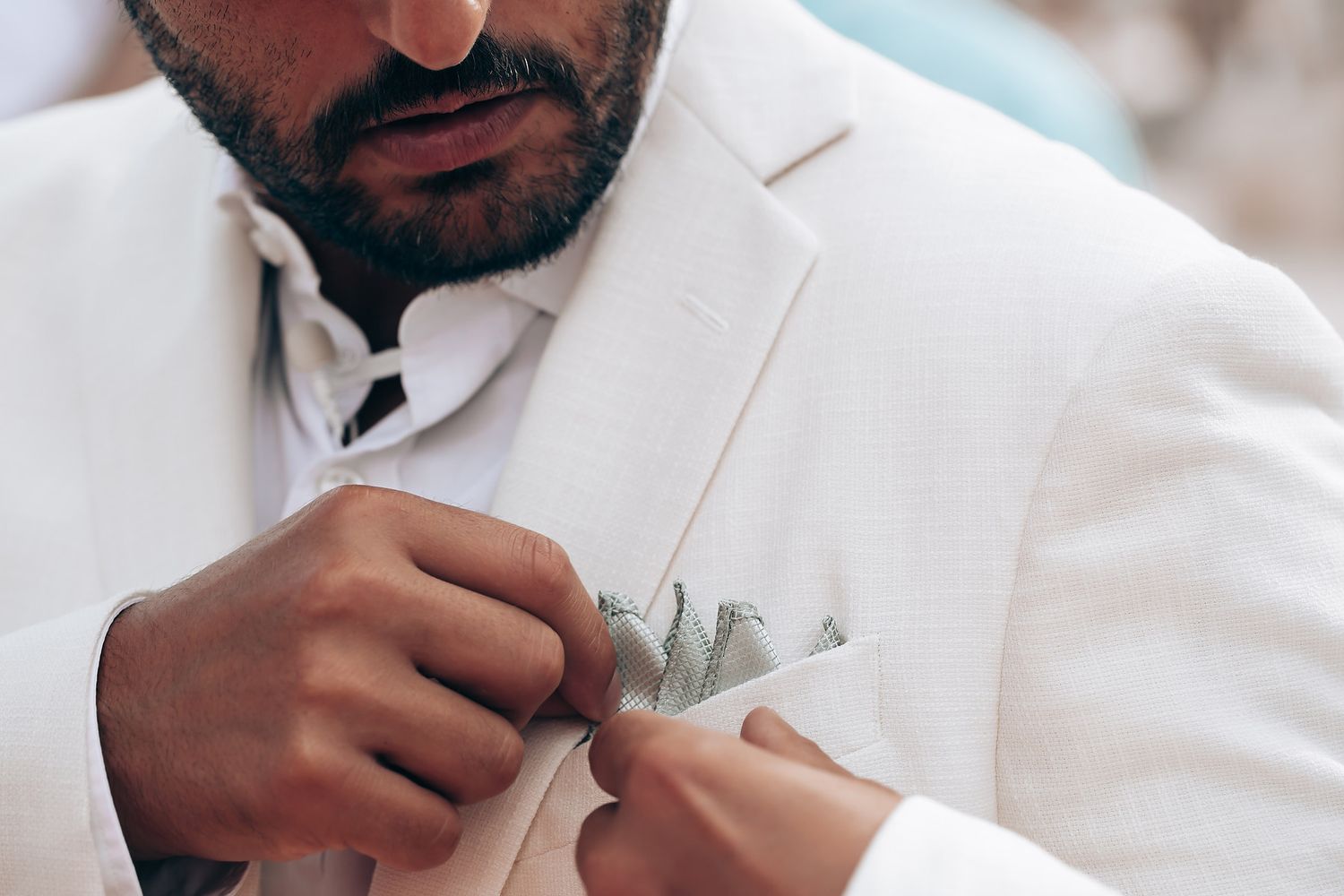 Men in white dress shirts adjusting their formal attire during wedding preparations.