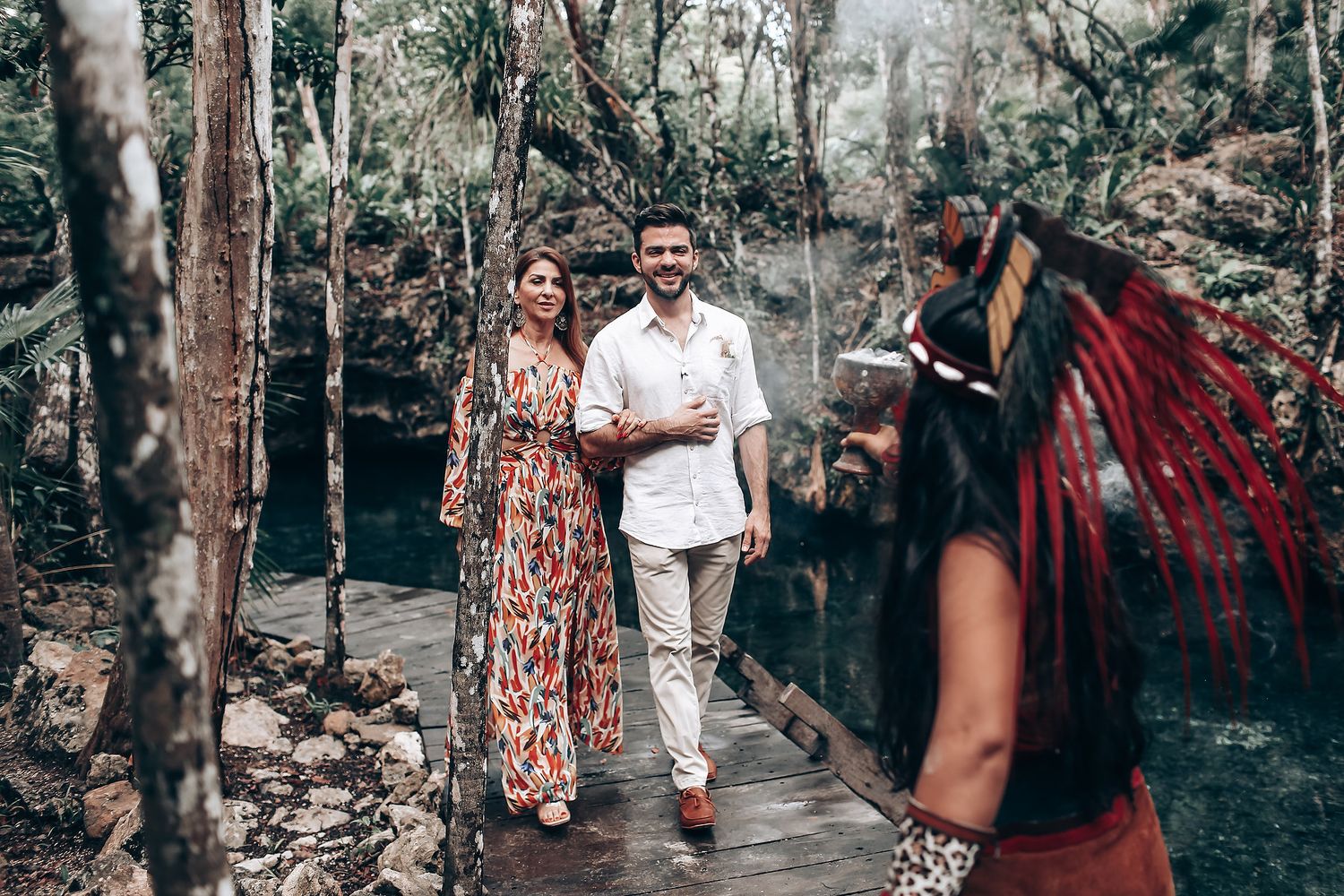A couple walks together through a wooded forest path during a romantic engagement photo session.