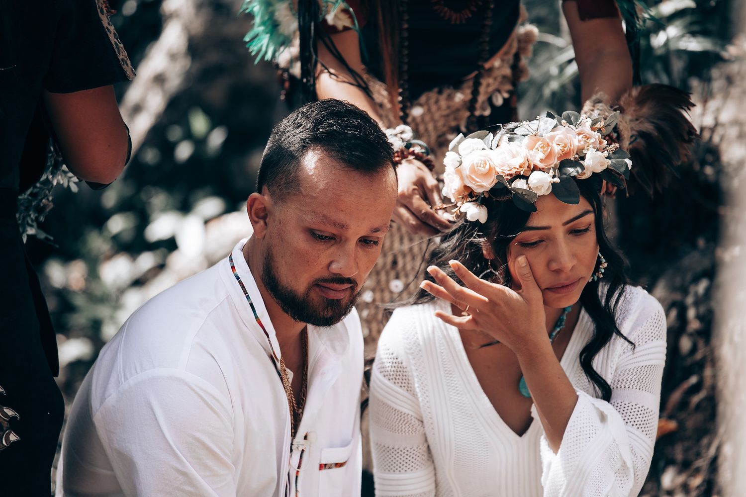 A group of people in white clothing gather outdoors for a casual celebration with drinks and laughter.