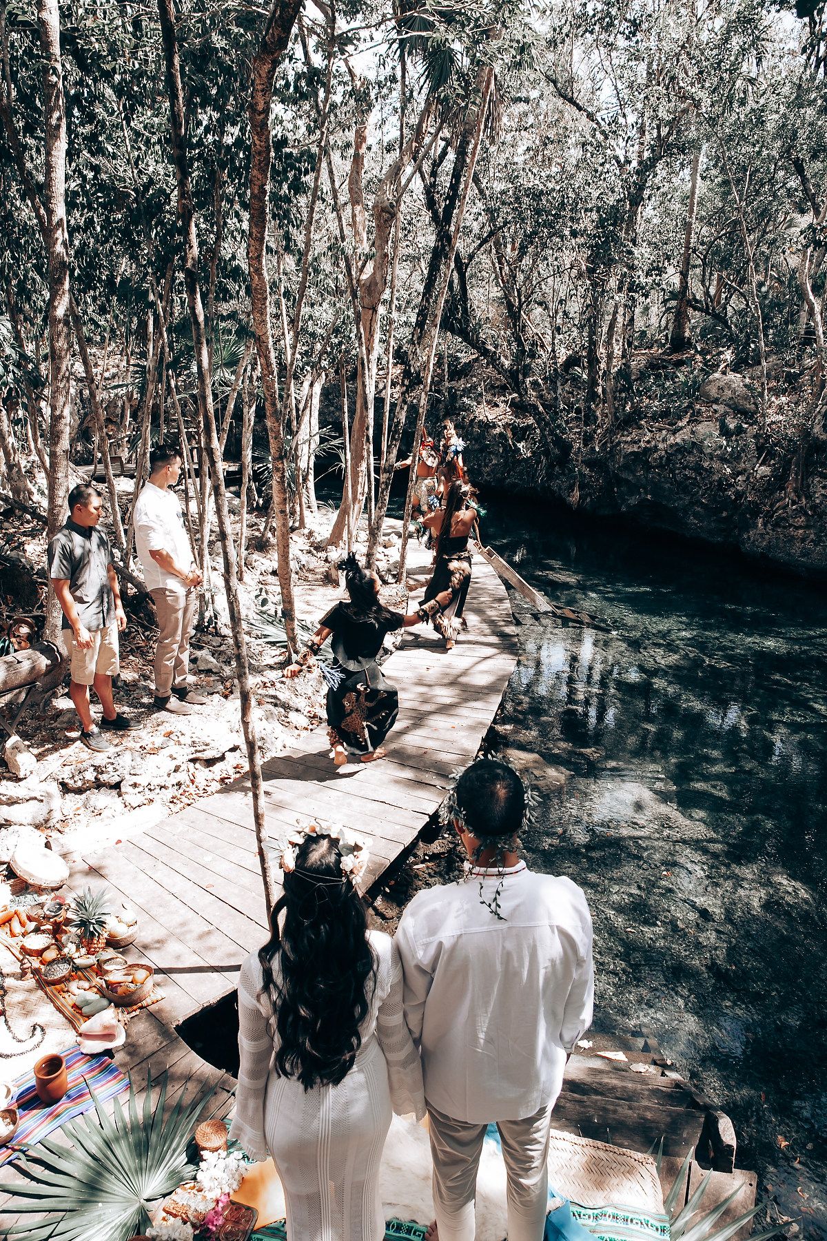 People gather on a wooden walkway in a forest for a spiritual ceremony.