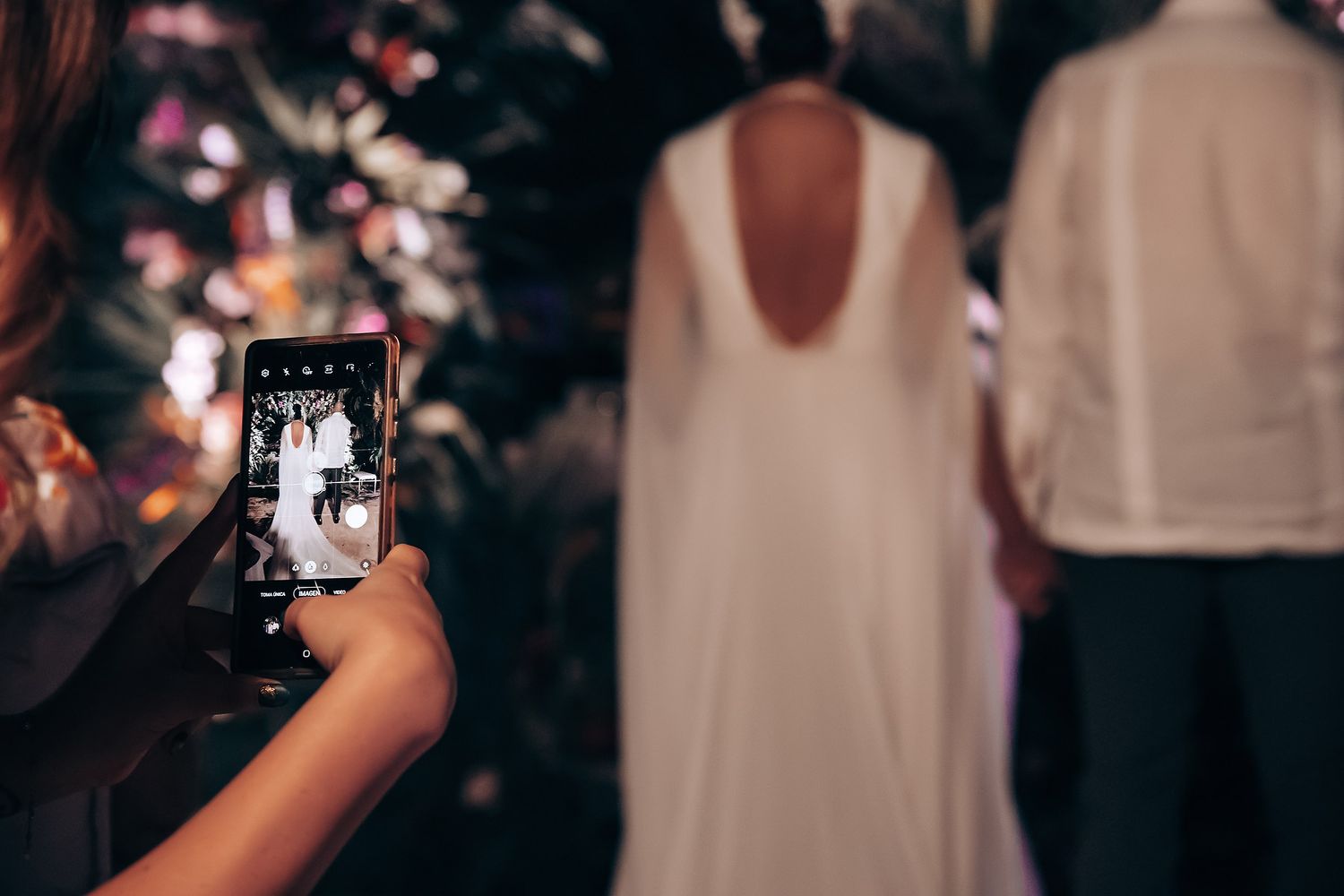 Guests dancing and celebrating at a lively nighttime wedding reception with festive lighting and decor.