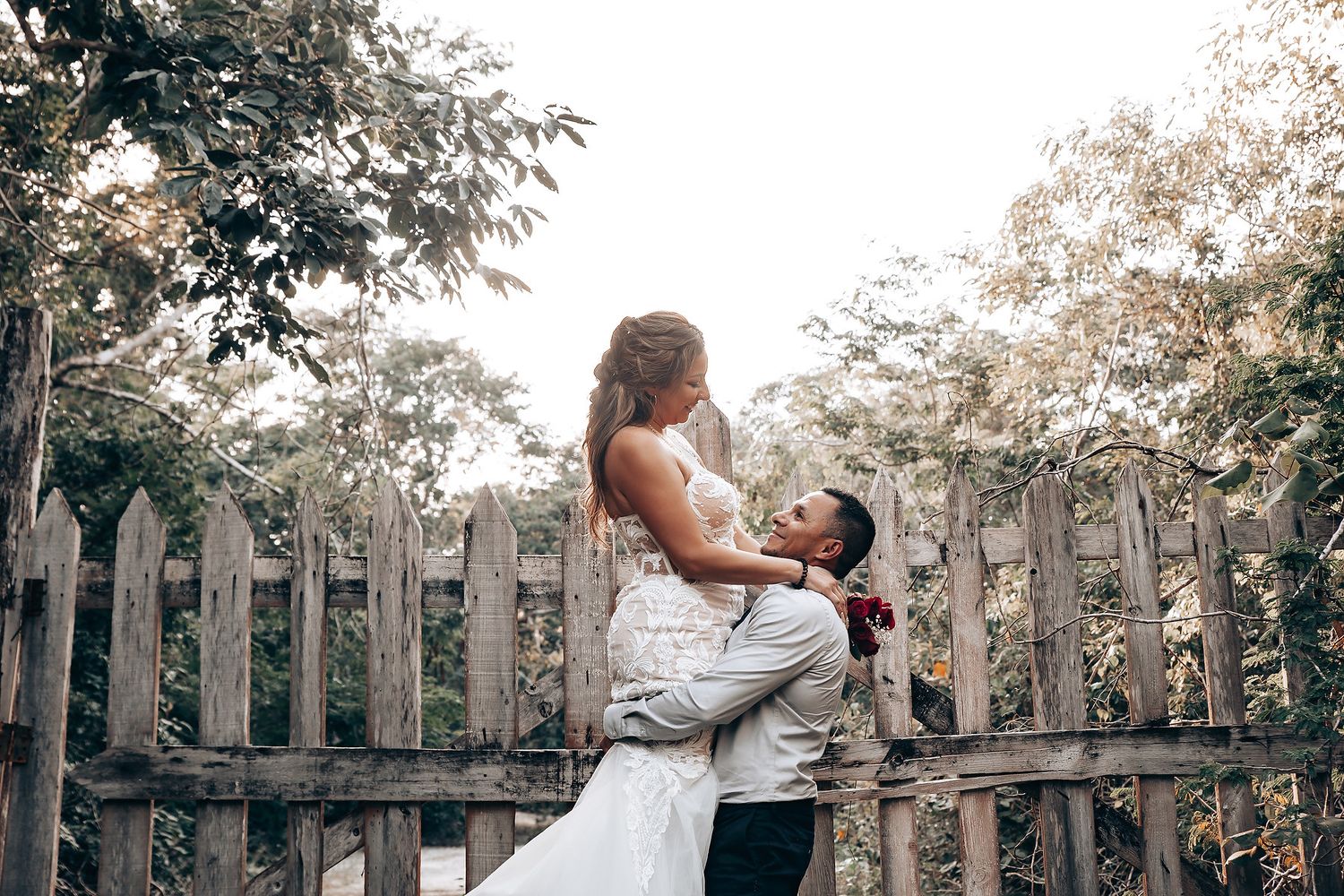 An elegant outdoor wedding portrait session with natural wooden fence backdrop.