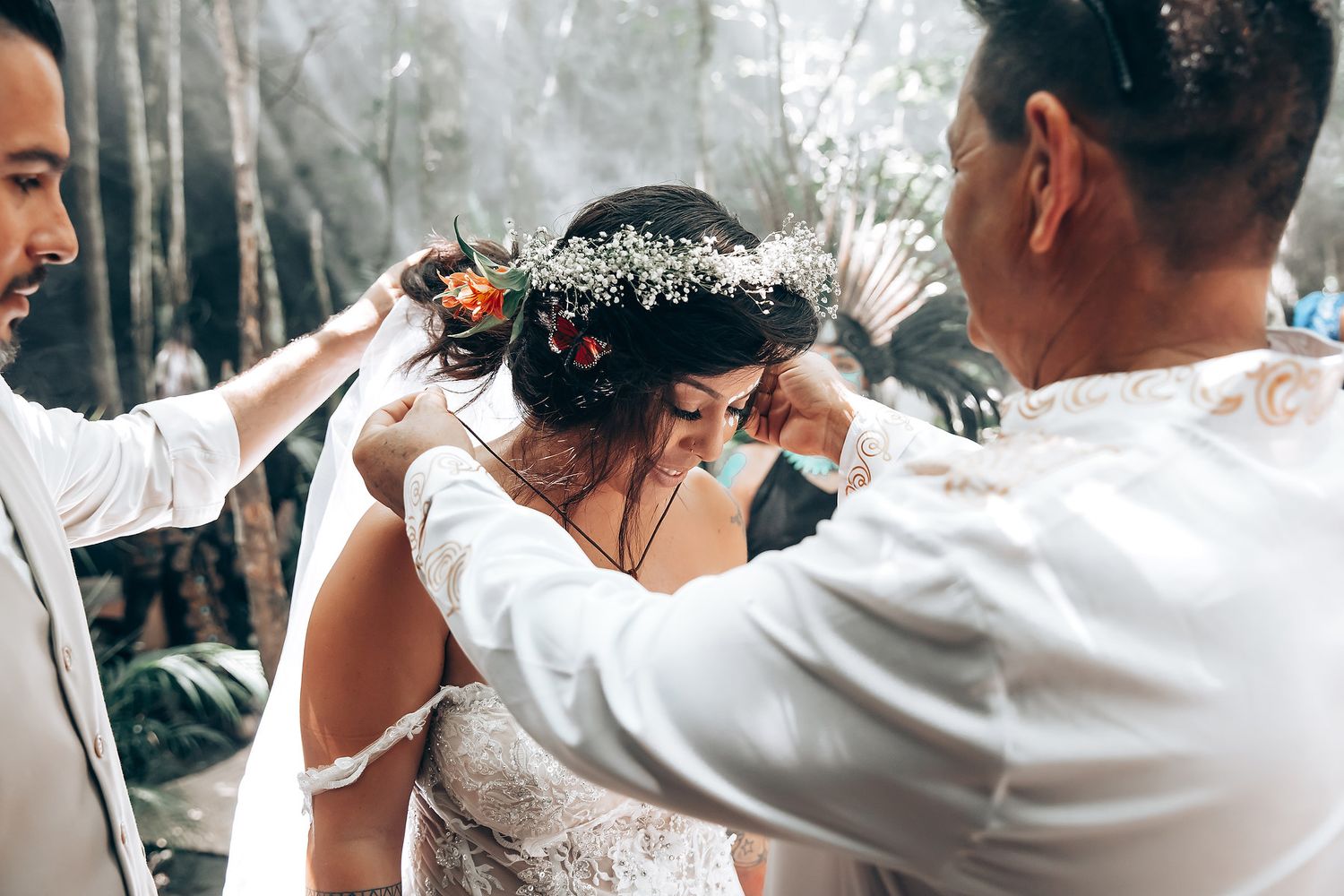 Wedding guests dance and celebrate at an outdoor reception surrounded by tropical foliage.