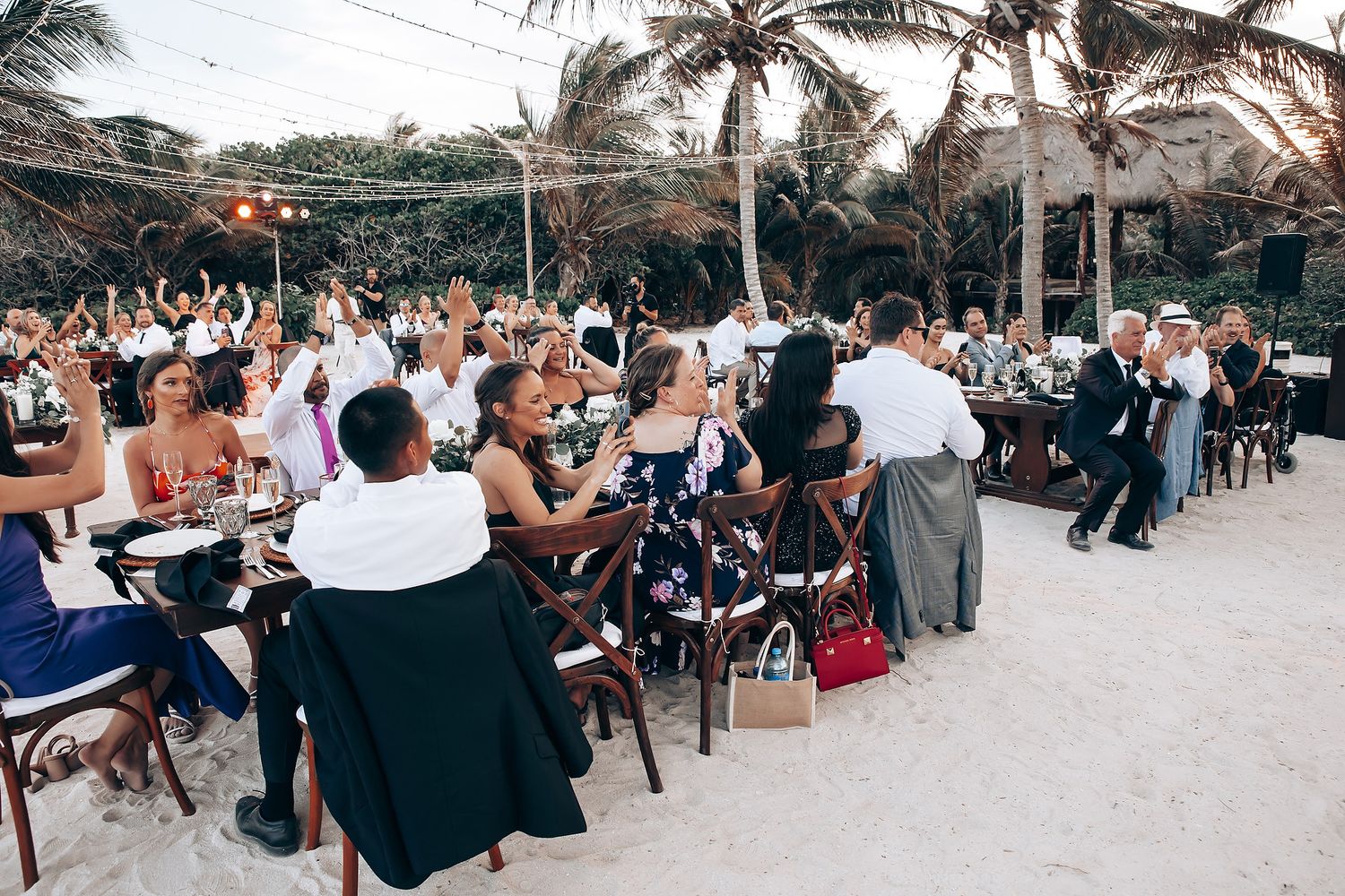 Outdoor wedding reception with guests seated in rows along a beachside venue.